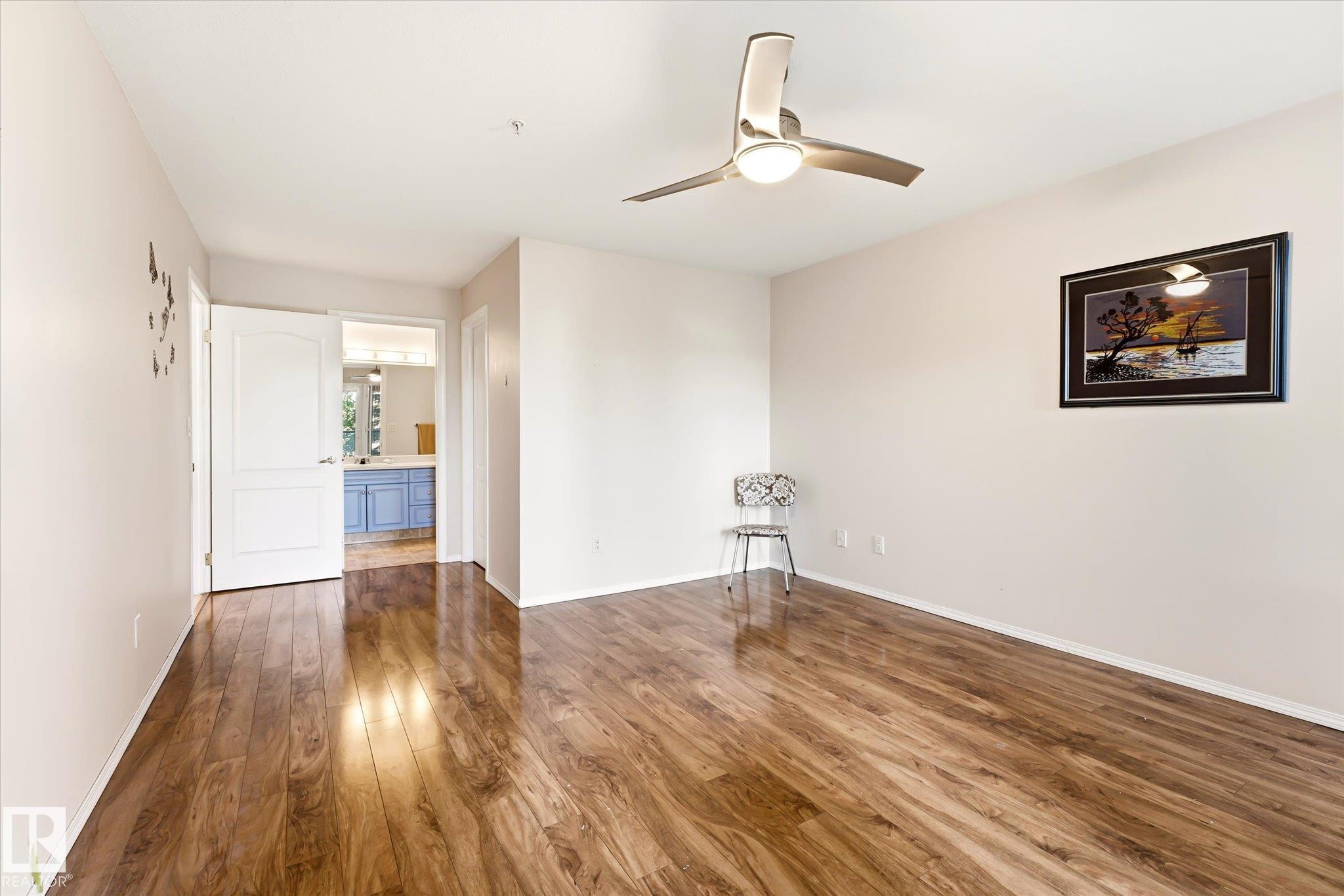 Expansive room featuring wood-finish flooring, a contemporary ceiling fan with integrated lighting, and neutral wall tones - #310 237 Youville Dr E Nw, Edmonton, AB - Indoor Photo Showing Other Room