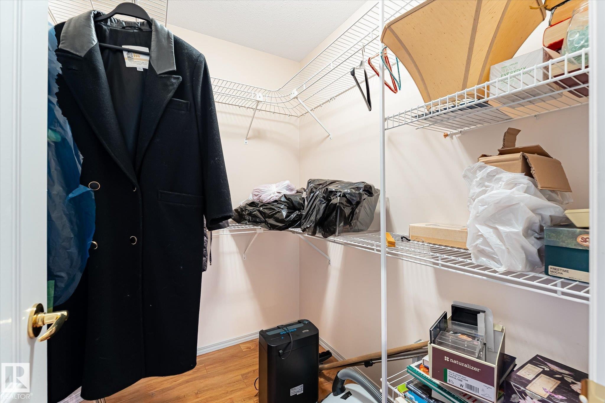 Walk-in closet featuring wire shelving, white walls, and wood-finish flooring - #310 237 Youville Dr E Nw, Edmonton, AB - Indoor With Storage