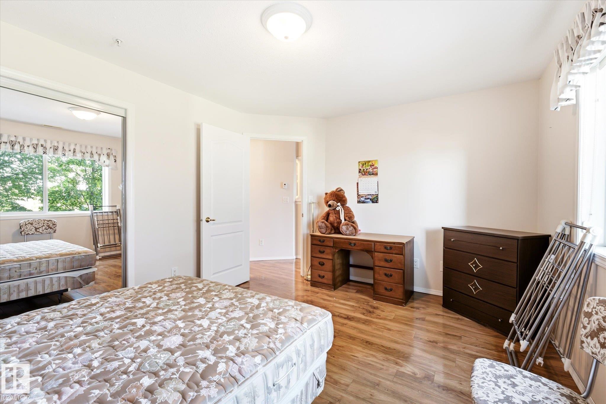 Room featuring wood-finish flooring, a double window, and white walls - #310 237 Youville Dr E Nw, Edmonton, AB - Indoor Photo Showing Bedroom