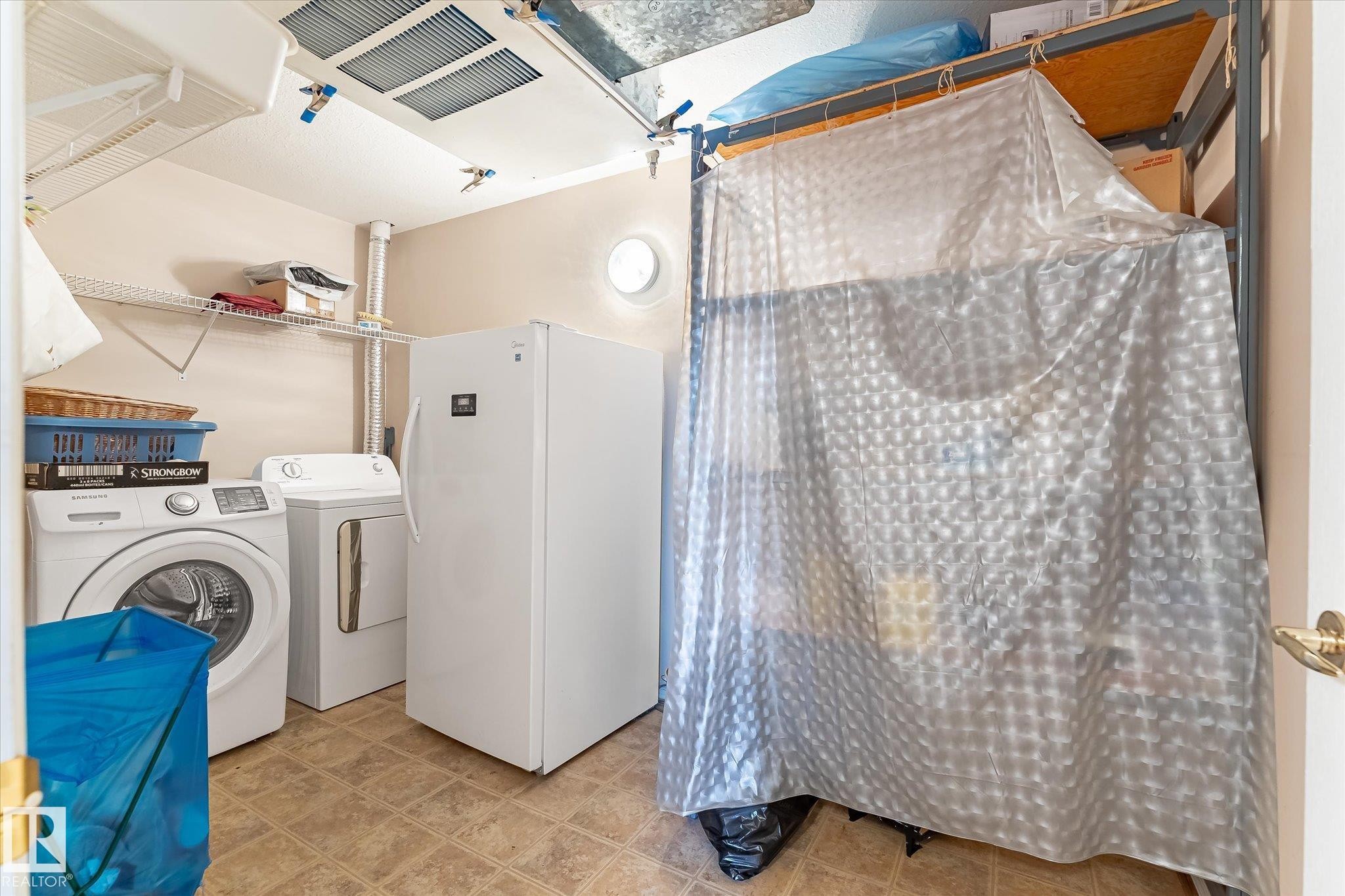 Dedicated utility room featuring patterned flooring, overhead shelving, and a wall-mounted circular light fixture - #310 237 Youville Dr E Nw, Edmonton, AB - Indoor Photo Showing Laundry Room
