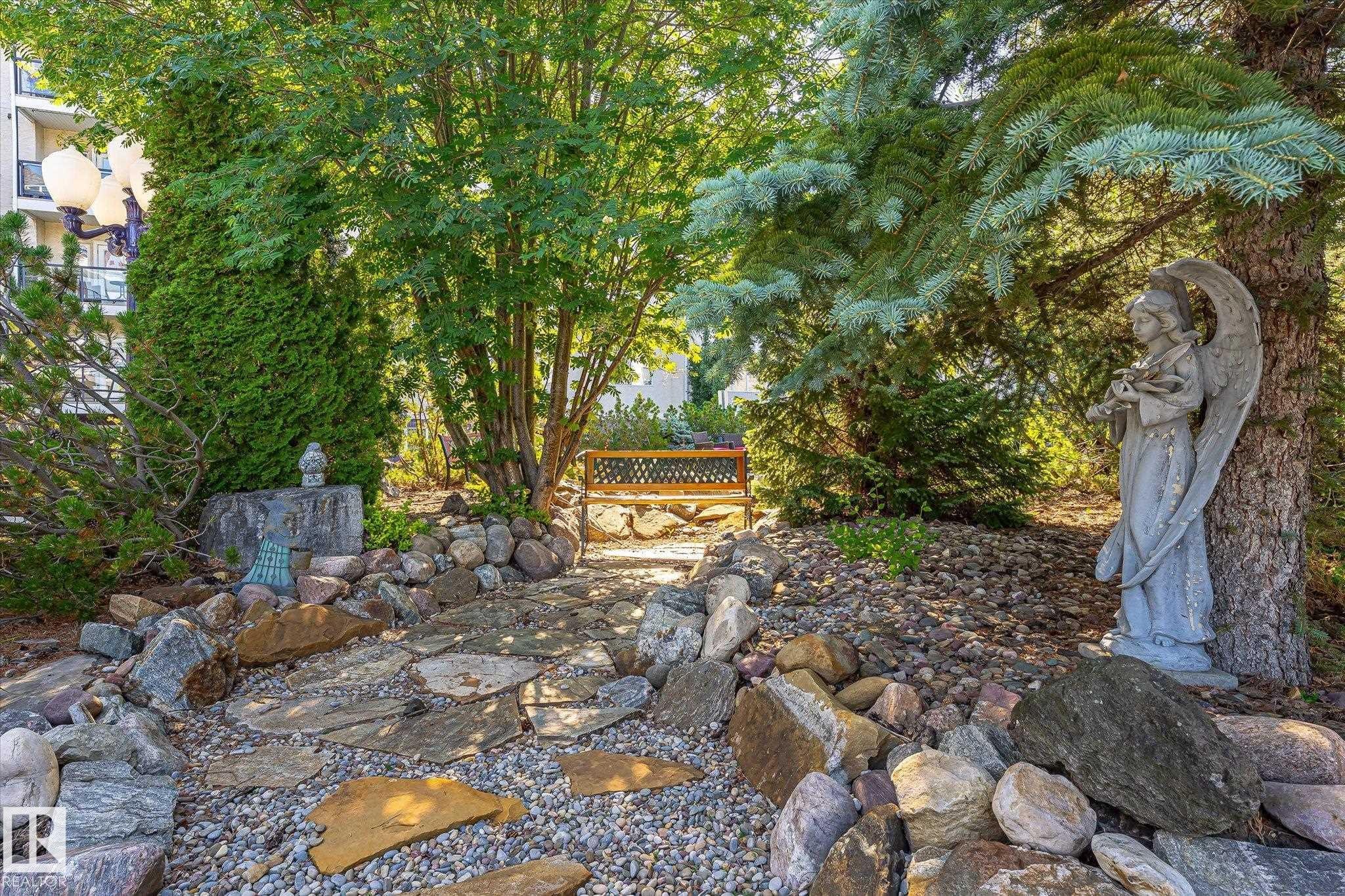 Landscaped garden pathway featuring flagstone steps and decorative river rock - #310 237 Youville Dr E Nw, Edmonton, AB - Outdoor