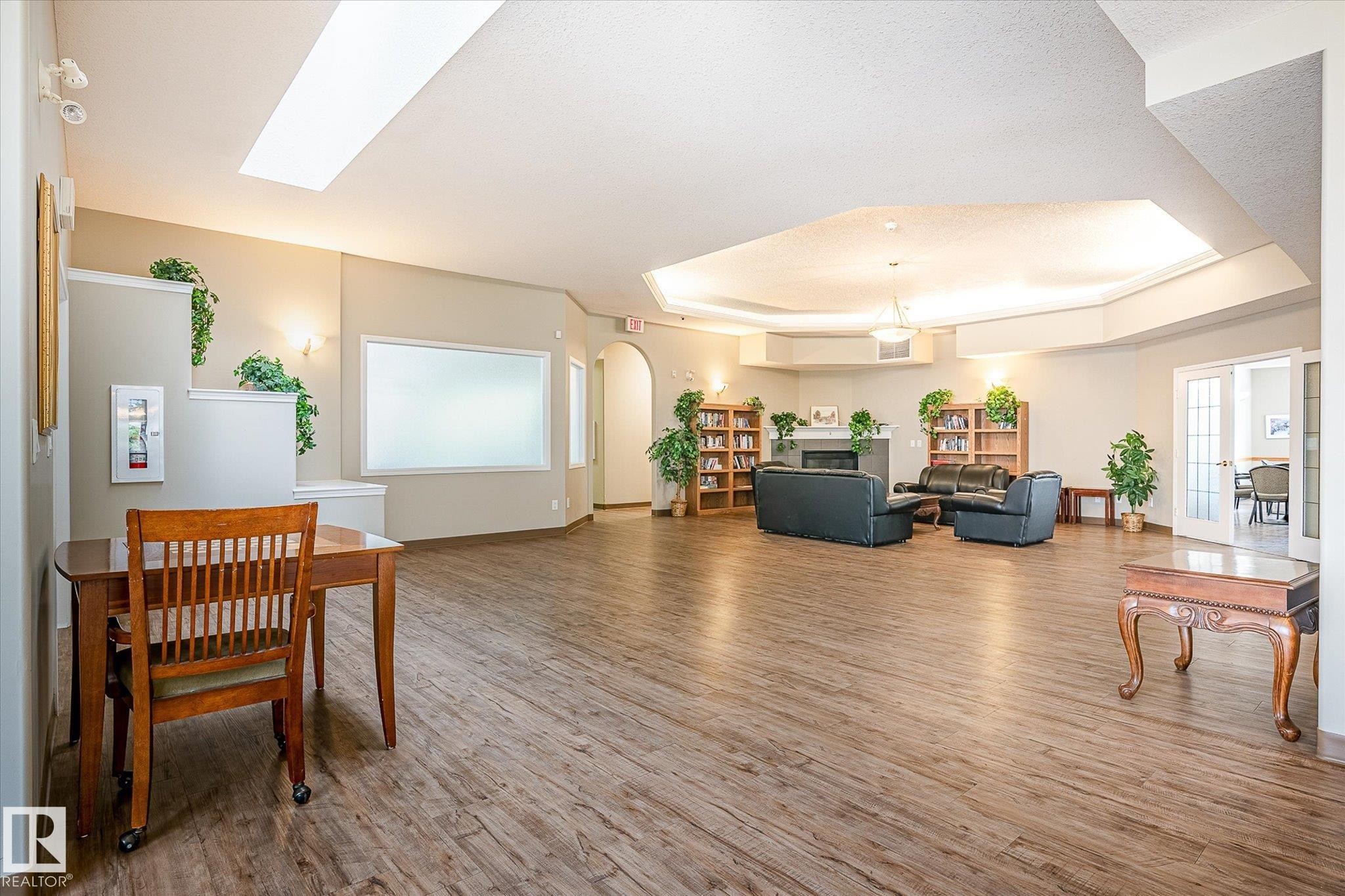 Spacious open-concept common area featuring wood-finish flooring, recessed lighting, and a skylight - #310 237 Youville Dr E Nw, Edmonton, AB - Indoor Photo Showing Other Room