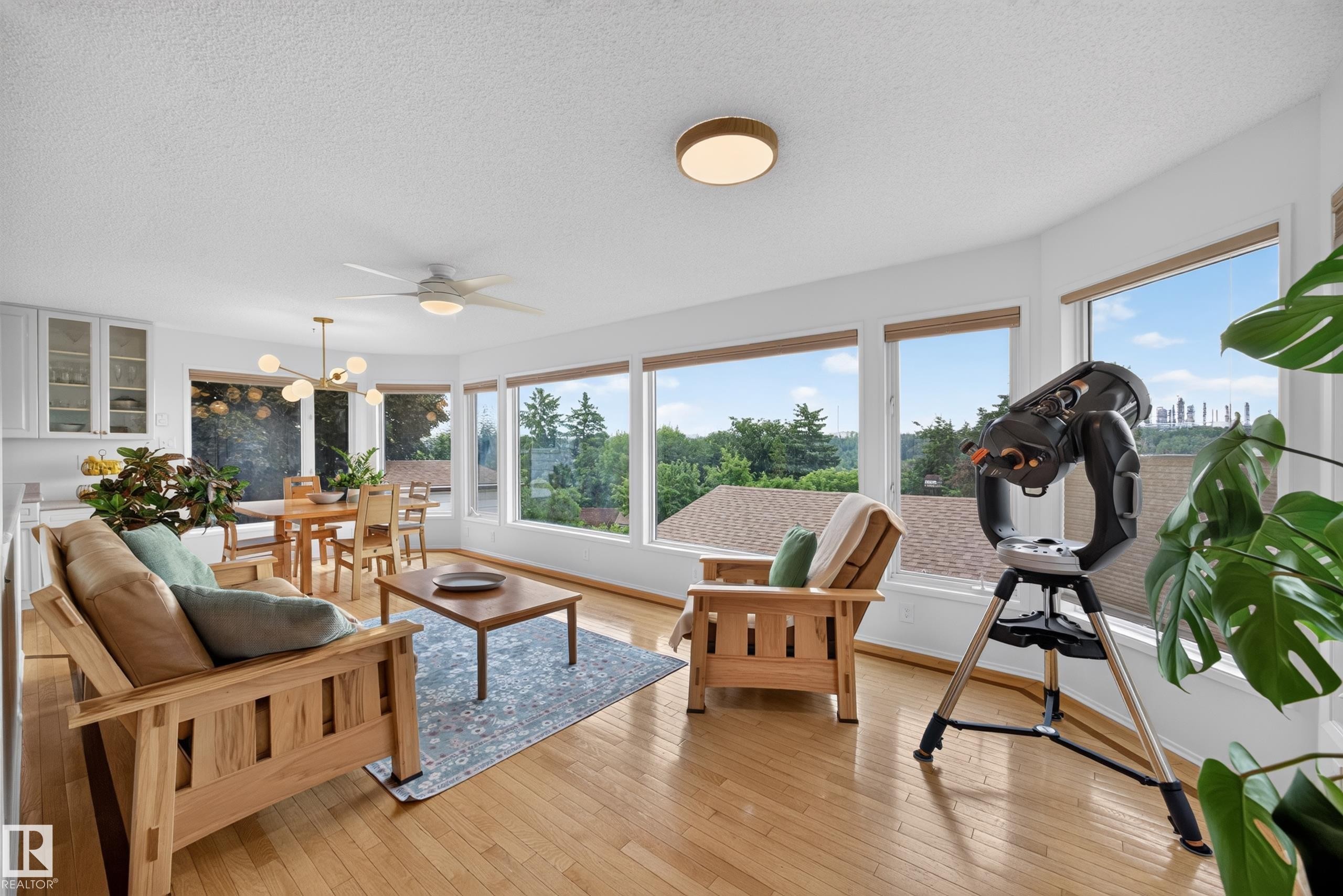 Open-concept living area featuring numerous large windows, wood-finish flooring, and white walls - 3411 103 Avenue Nw, Edmonton, AB