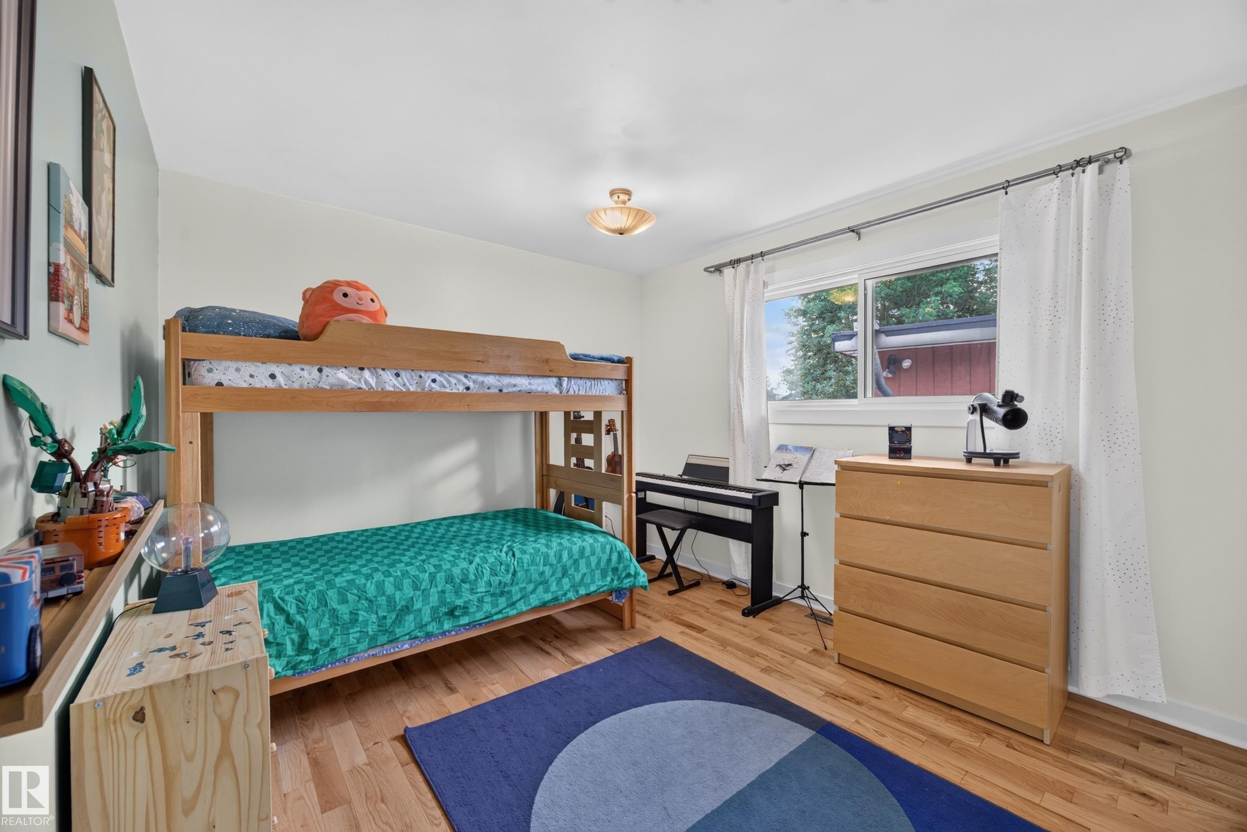 Bedroom featuring light wood-finish flooring, a double window with white curtain panels, a recessed ceiling light fixture, and crown molding - 3411 103 Avenue Nw, Edmonton, AB