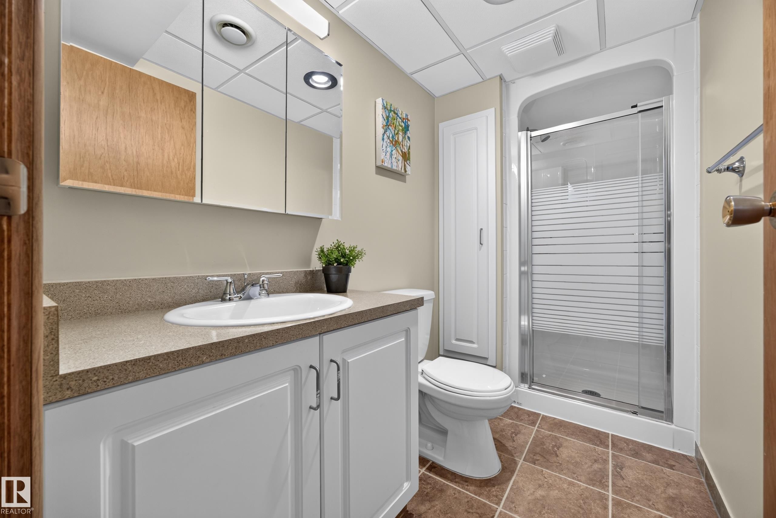 Bathroom featuring a white vanity with recessed panel doors, a durable countertop, and a glass-enclosed shower - 3411 103 Avenue Nw, Edmonton, AB