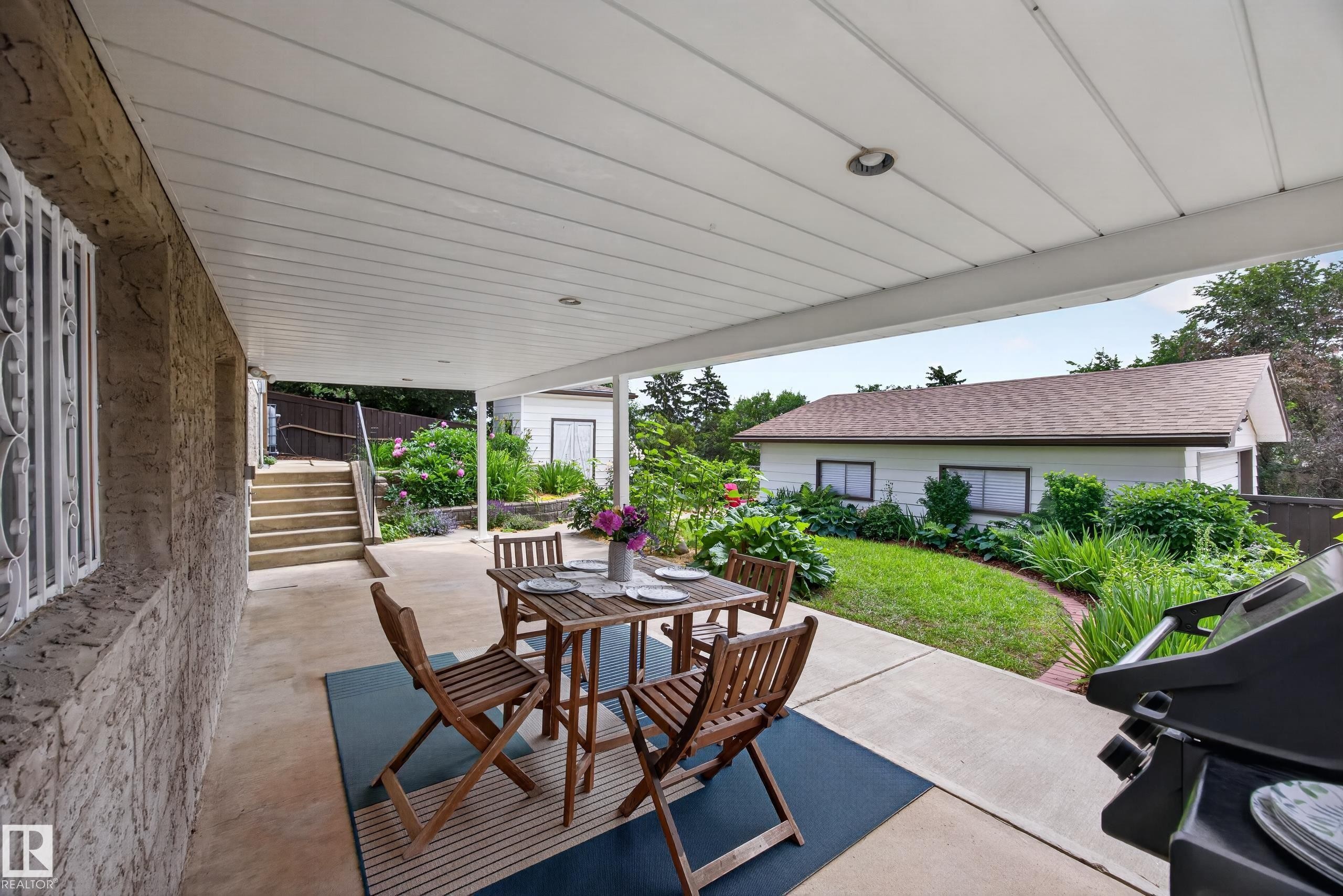 Covered concrete patio with recessed lighting, featuring an exterior wall with decorative security bars - 3411 103 Avenue Nw, Edmonton, AB