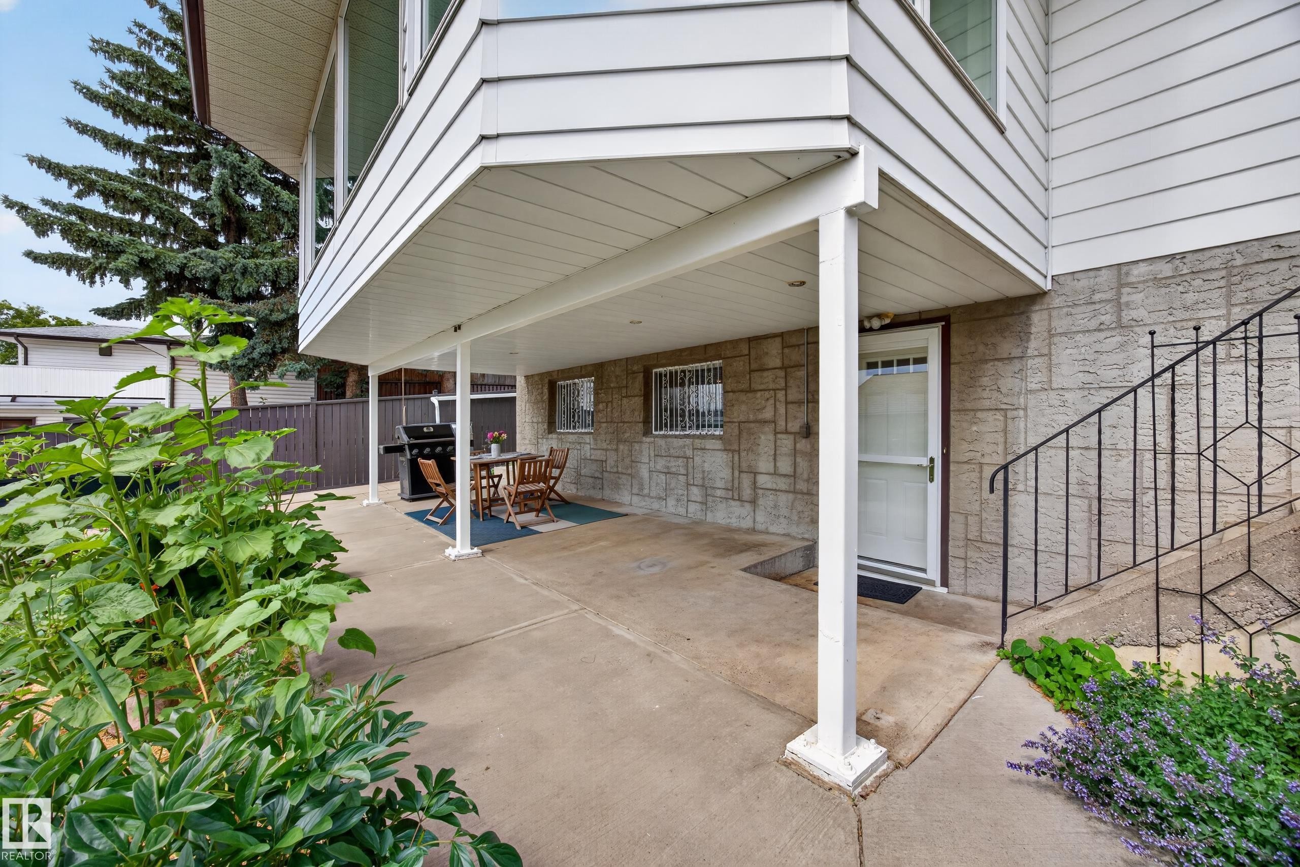 Covered concrete patio with white support columns - 3411 103 Avenue Nw, Edmonton, AB