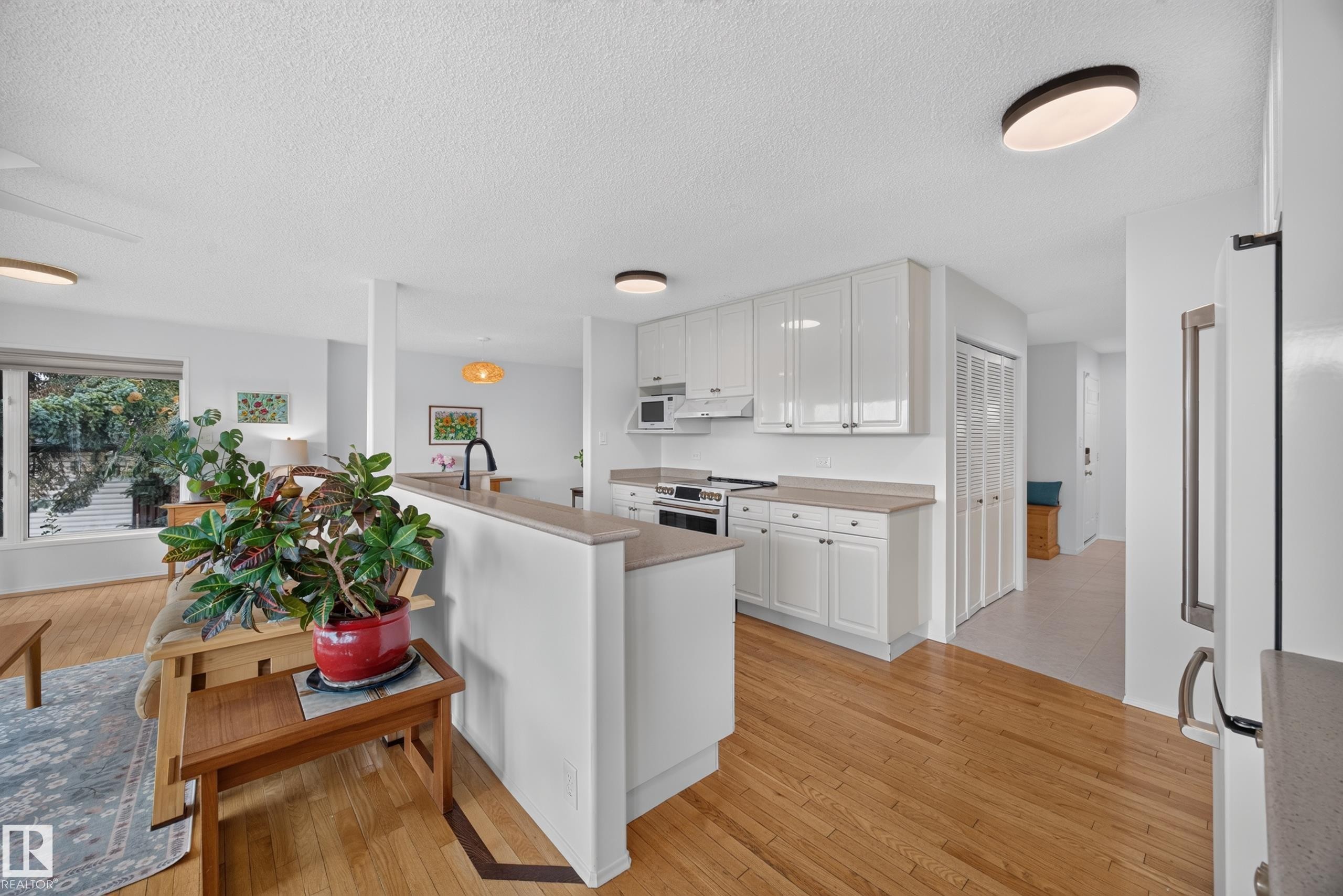 Contemporary kitchen featuring white cabinetry, light countertops, and a black faucet - 3411 103 Avenue Nw, Edmonton, AB