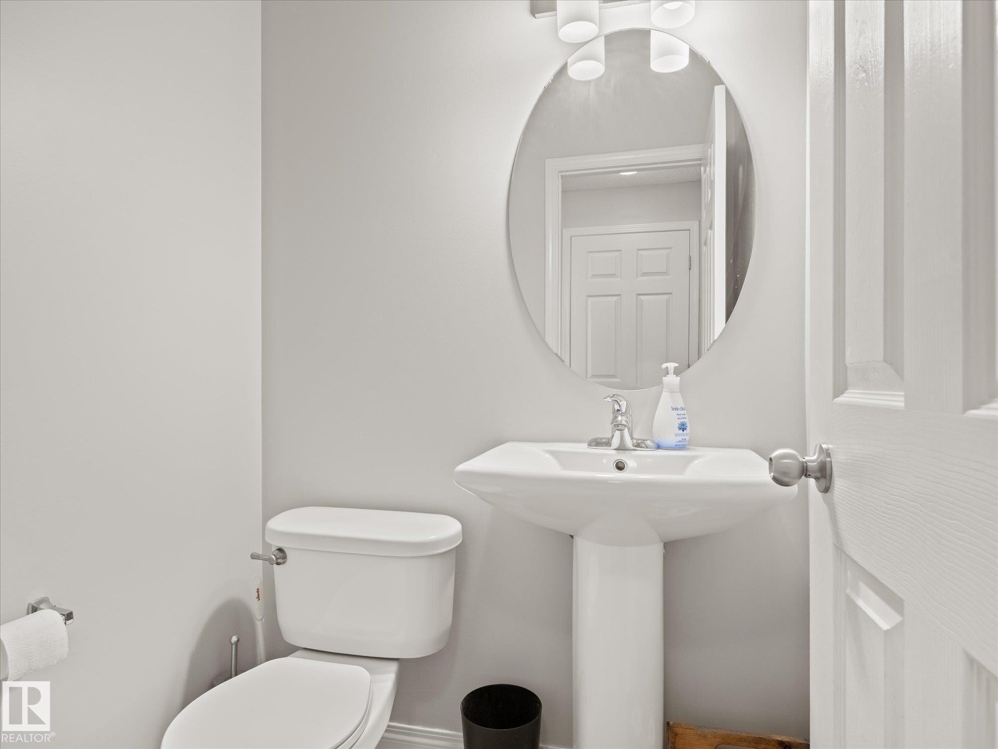 Pedestal sink with a polished chrome faucet and an oval mirror - 473 Orchards Boulevard Sw, Edmonton, AB - Indoor Photo Showing Bathroom