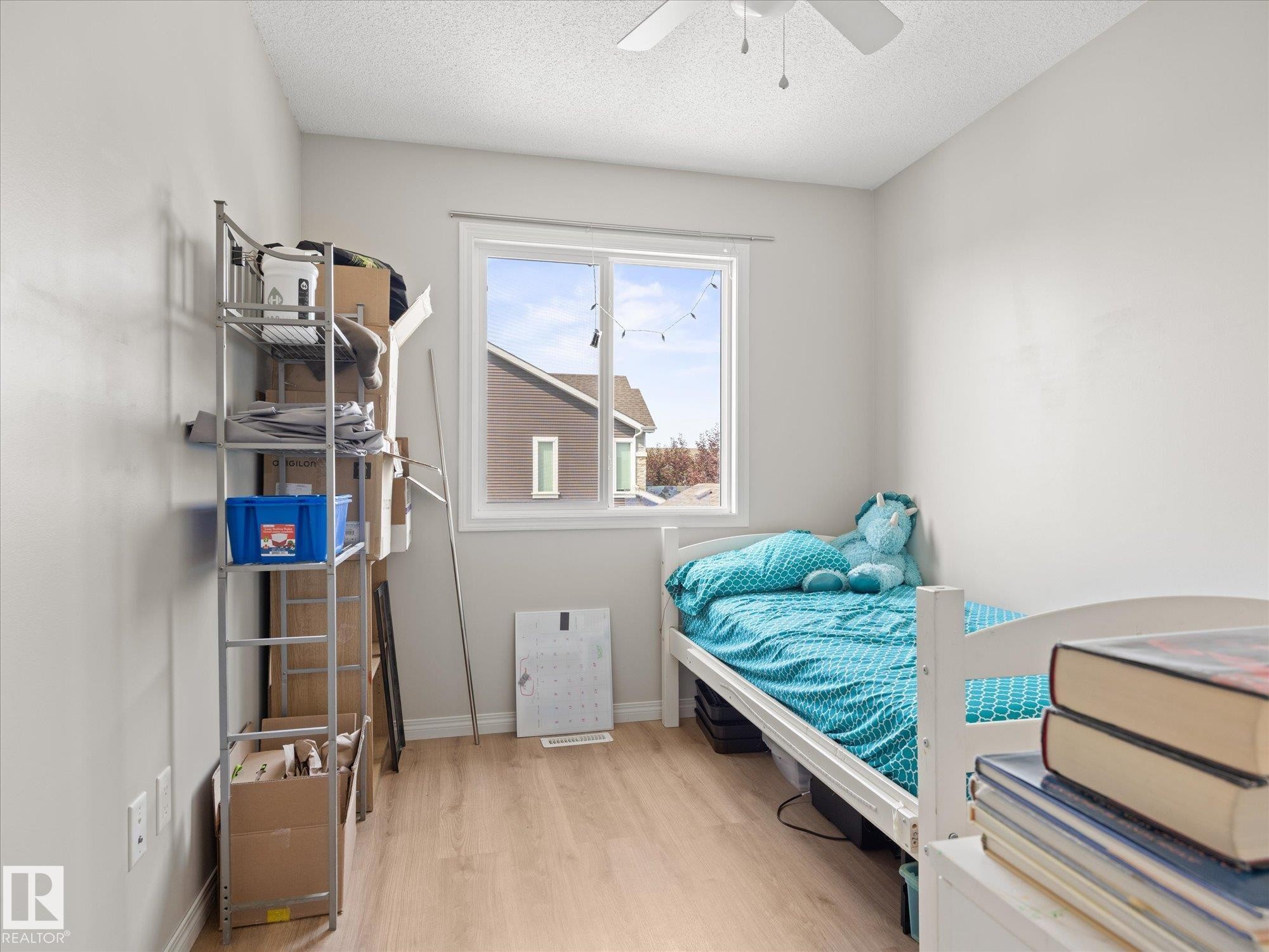 Neutral wall paint, wood-finish flooring, and a ceiling fan with light fixture - 473 Orchards Boulevard Sw, Edmonton, AB - Indoor Photo Showing Bedroom