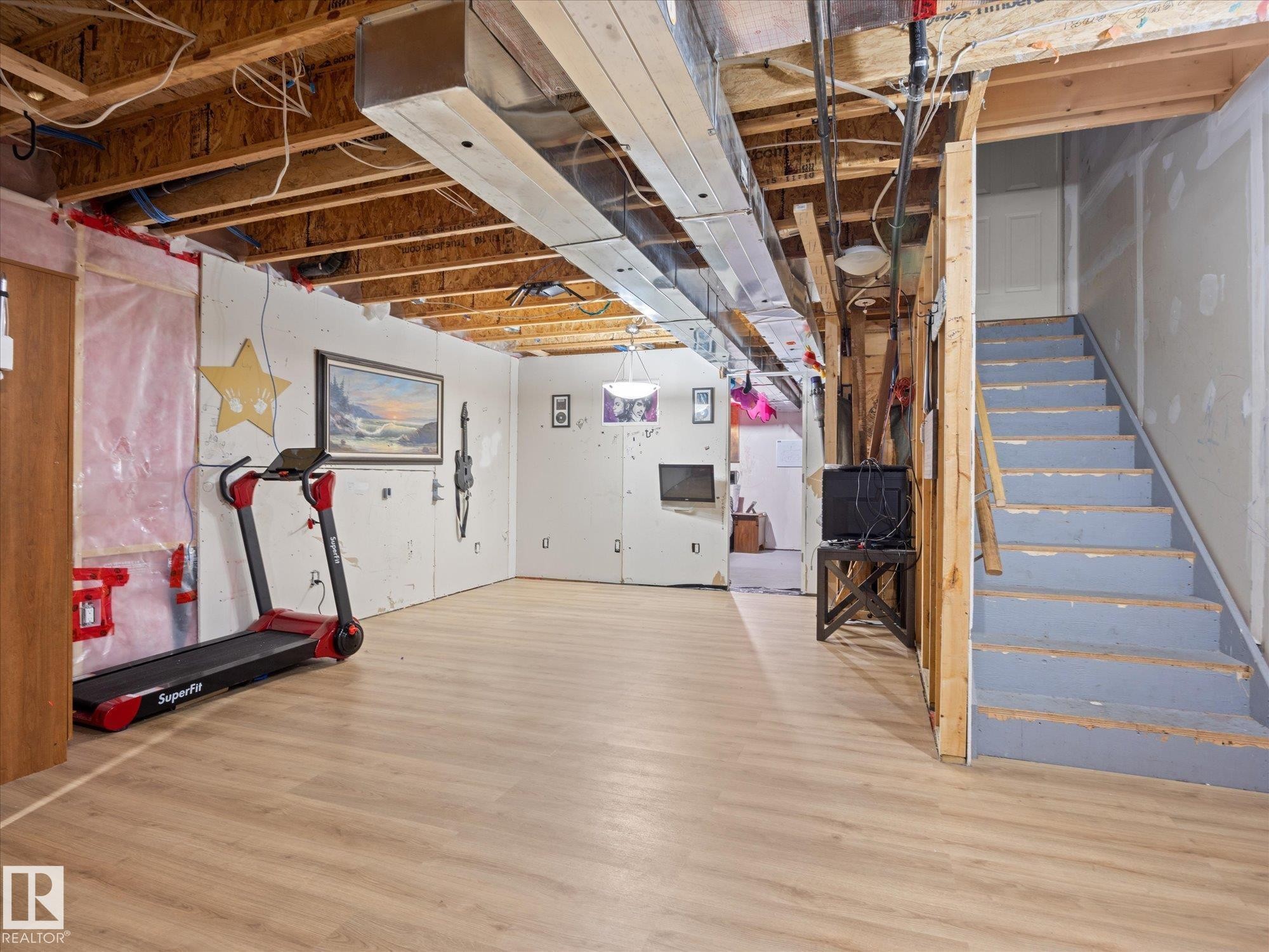 Lower level featuring wood-finish flooring, exposed ceiling joists, partially finished walls, and visible ductwork - 473 Orchards Boulevard Sw, Edmonton, AB - Indoor Photo Showing Basement