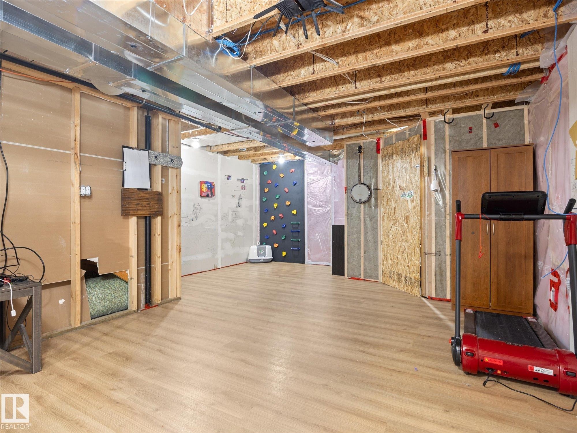Unfinished basement space featuring exposed wood joists and subflooring, partial wall framing, and wood-finish flooring - 473 Orchards Boulevard Sw, Edmonton, AB - Indoor Photo Showing Basement
