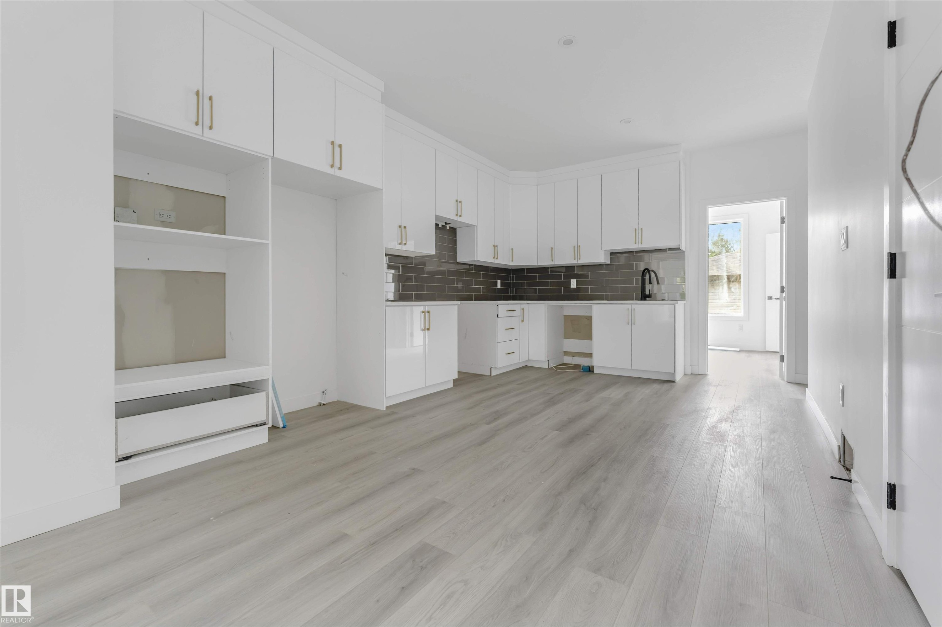 Kitchen area featuring white cabinetry, gold-tone hardware, and a dark subway tile backsplash - 3605 112 Ave, Edmonton, AB