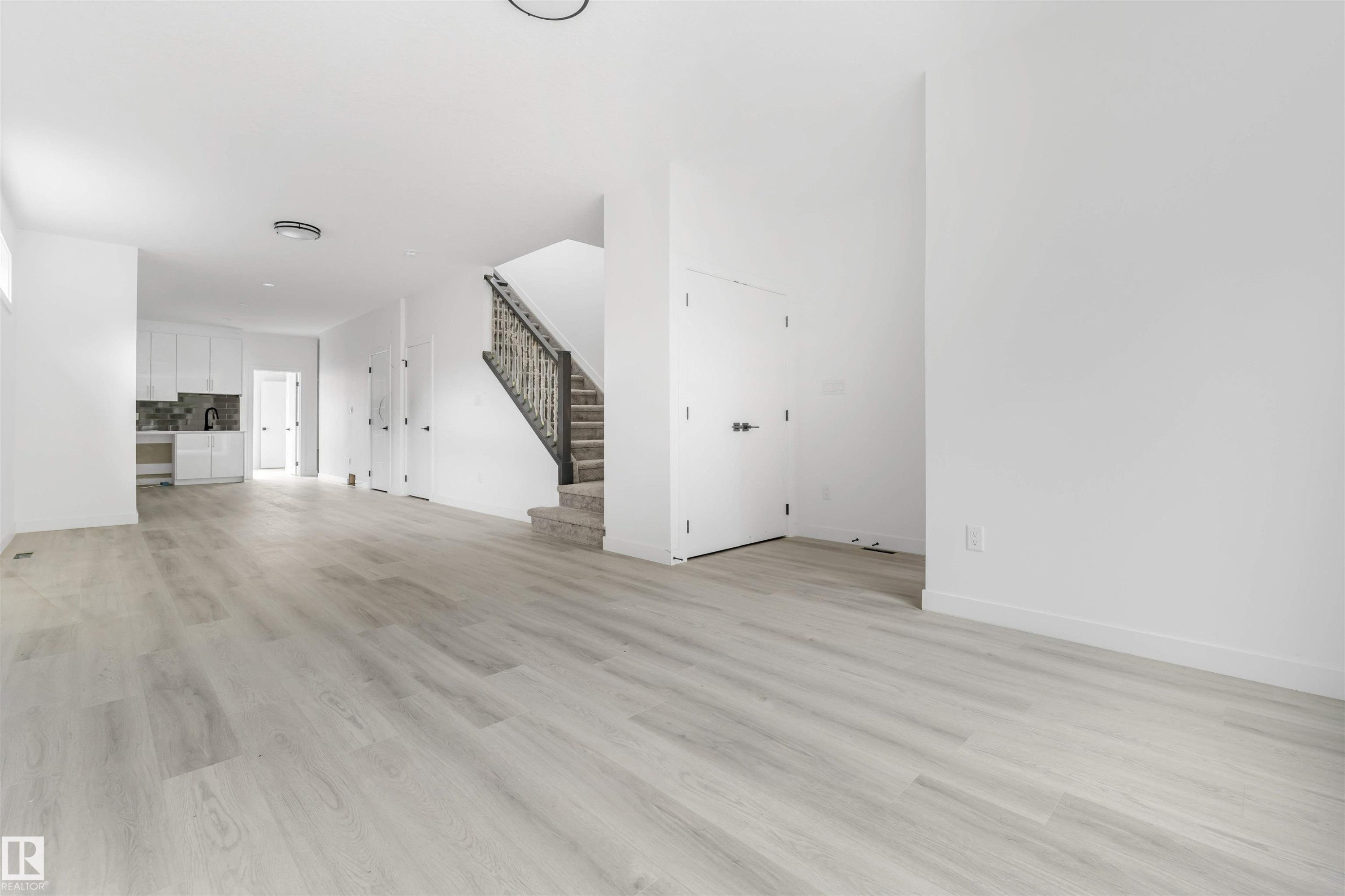 Open-concept living area featuring light wood-finish flooring, white walls, and recessed lighting - 3605 112 Ave, Edmonton, AB