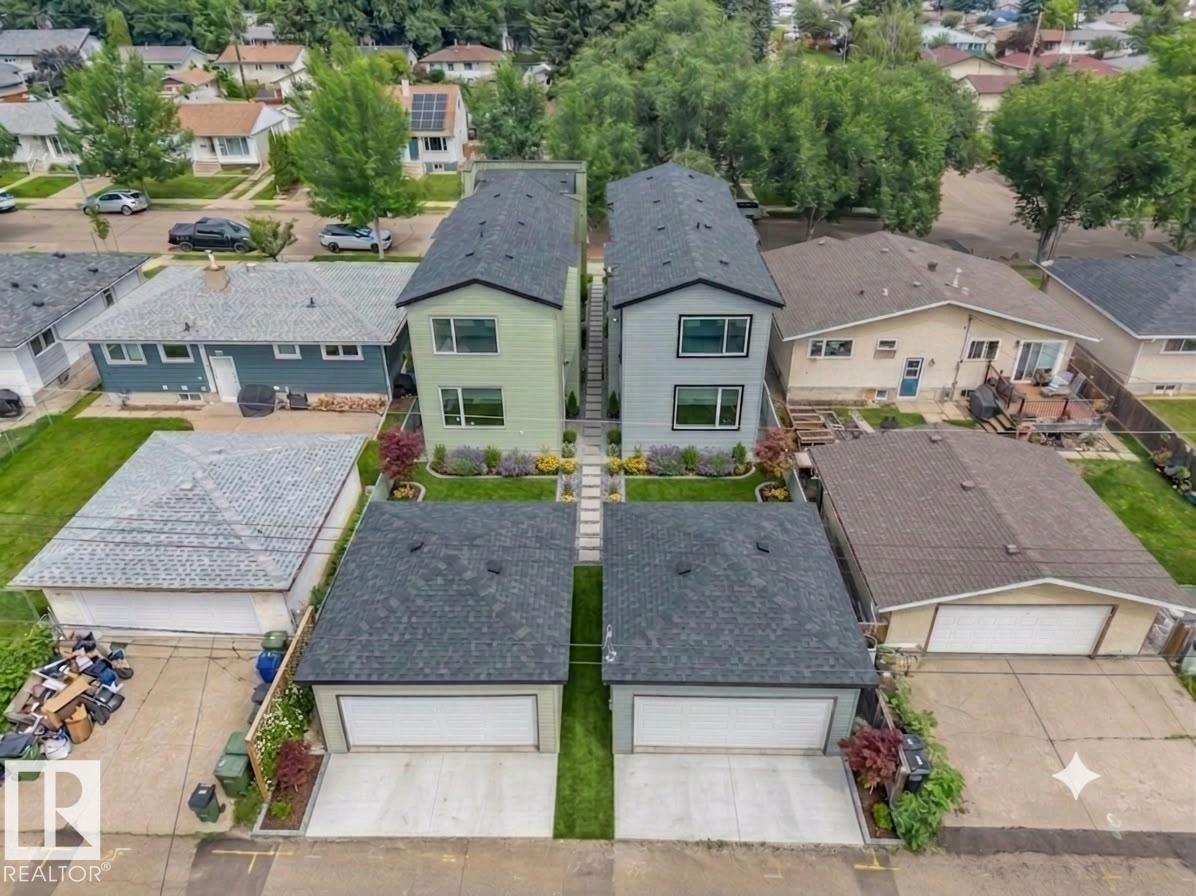 Twin modern homes featuring light green and light grey facades, each with a dedicated detached garage - 3605 112 Ave, Edmonton, AB