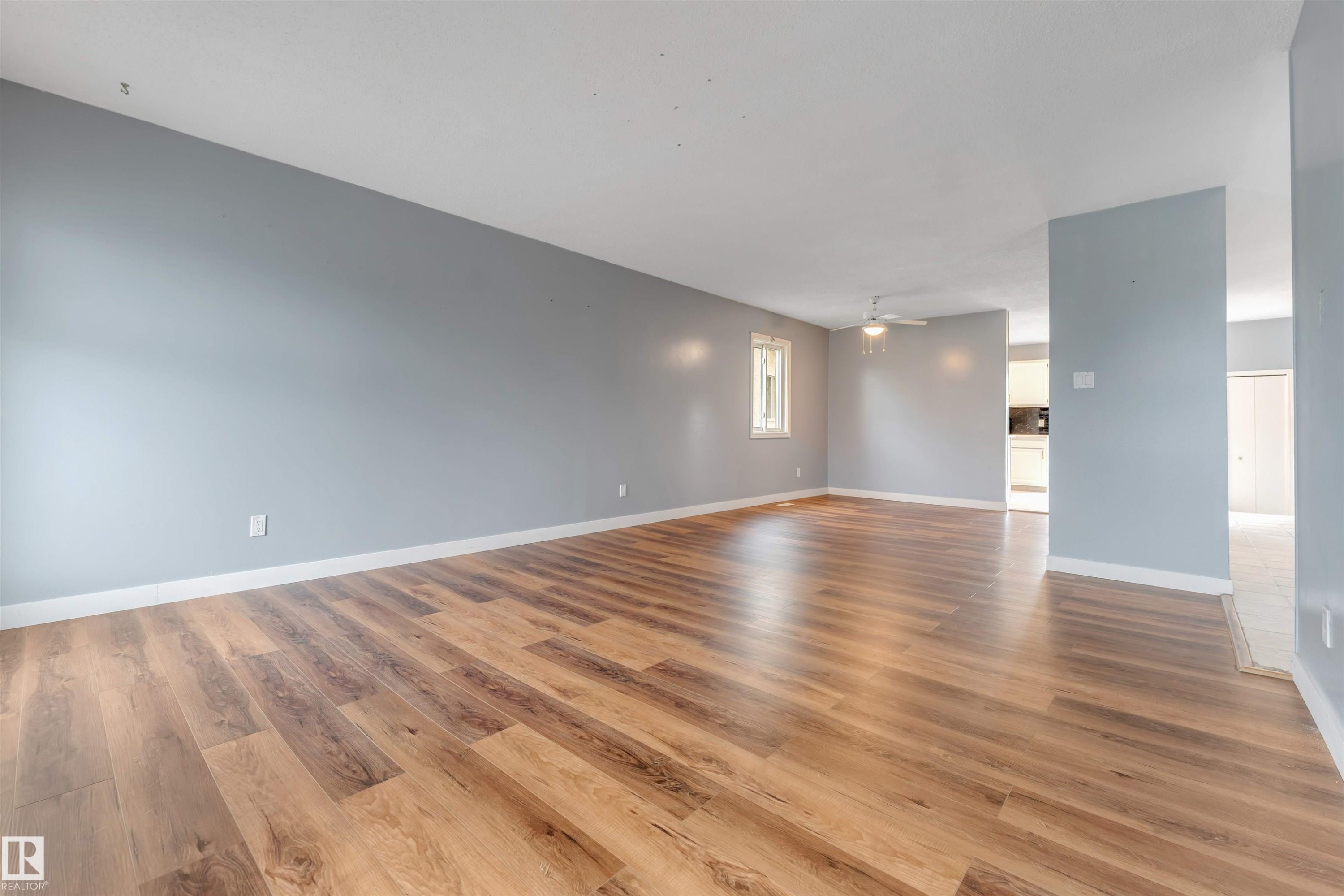 Spacious room featuring wood-finish flooring, light blue walls, and white baseboards - 193 Woodvale Road W, Edmonton, AB