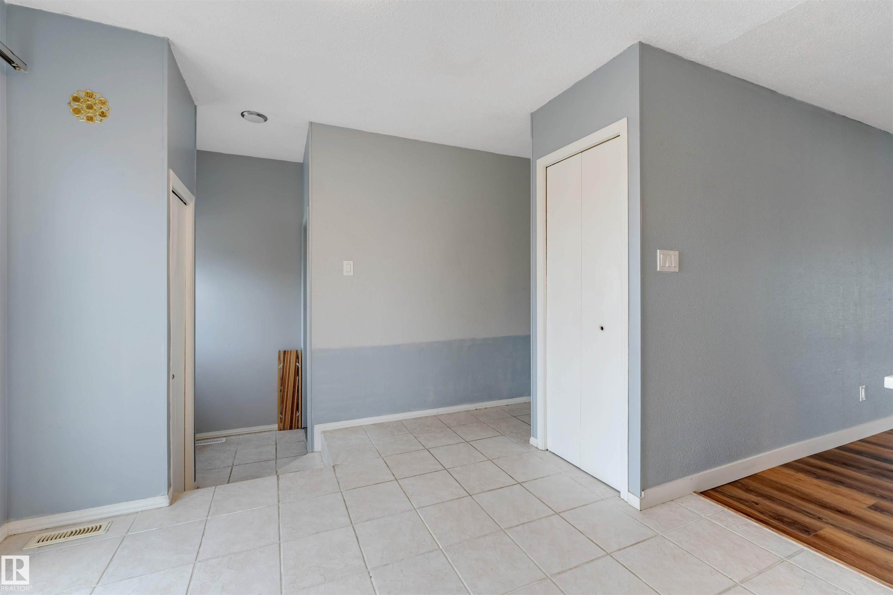 Tiled entryway with light gray walls, white trim, and a white bi-fold door - 193 Woodvale Road W, Edmonton, AB
