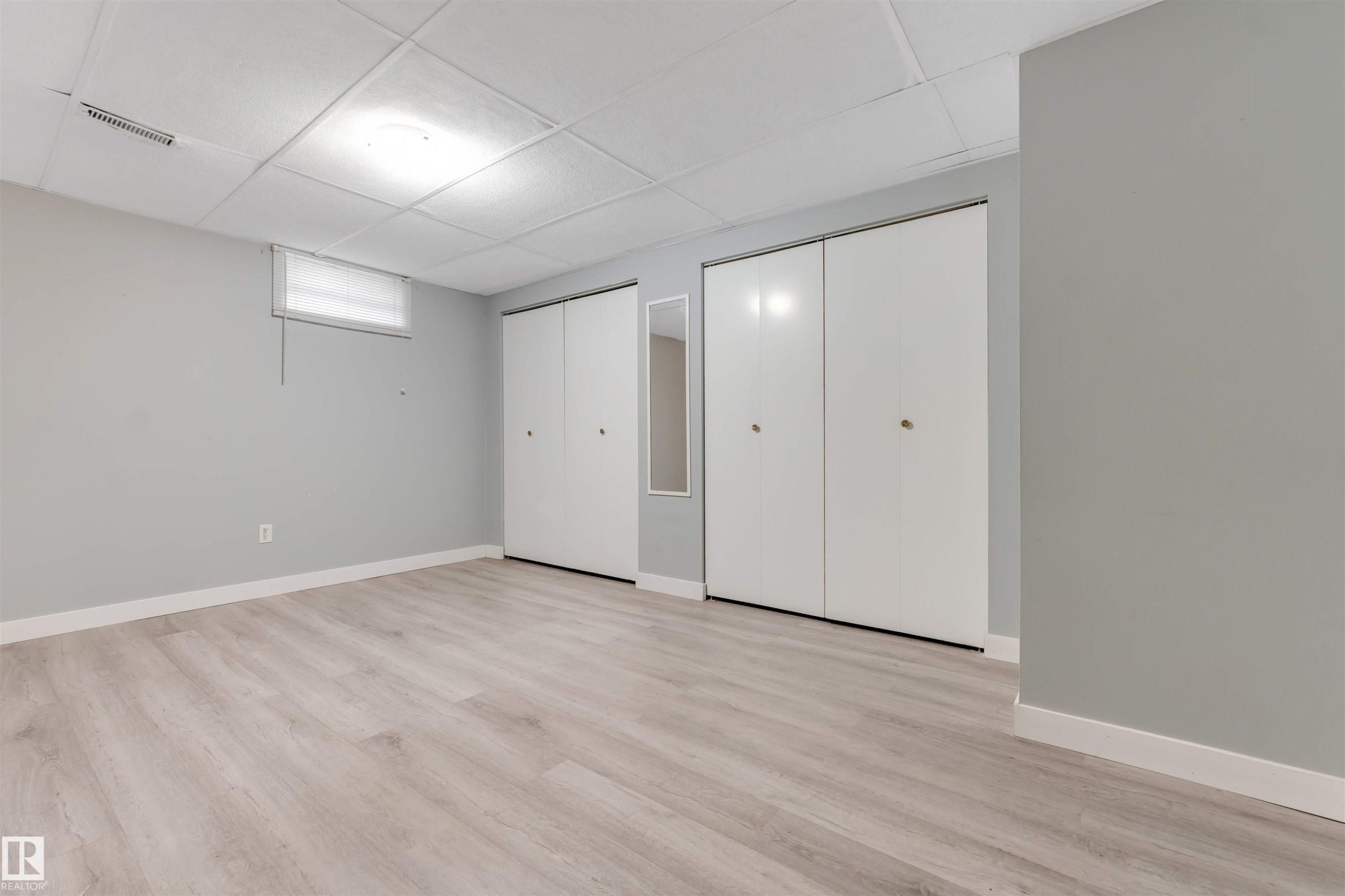 Spacious room featuring light wood-finish flooring, light gray walls, and white baseboards - 193 Woodvale Road W, Edmonton, AB