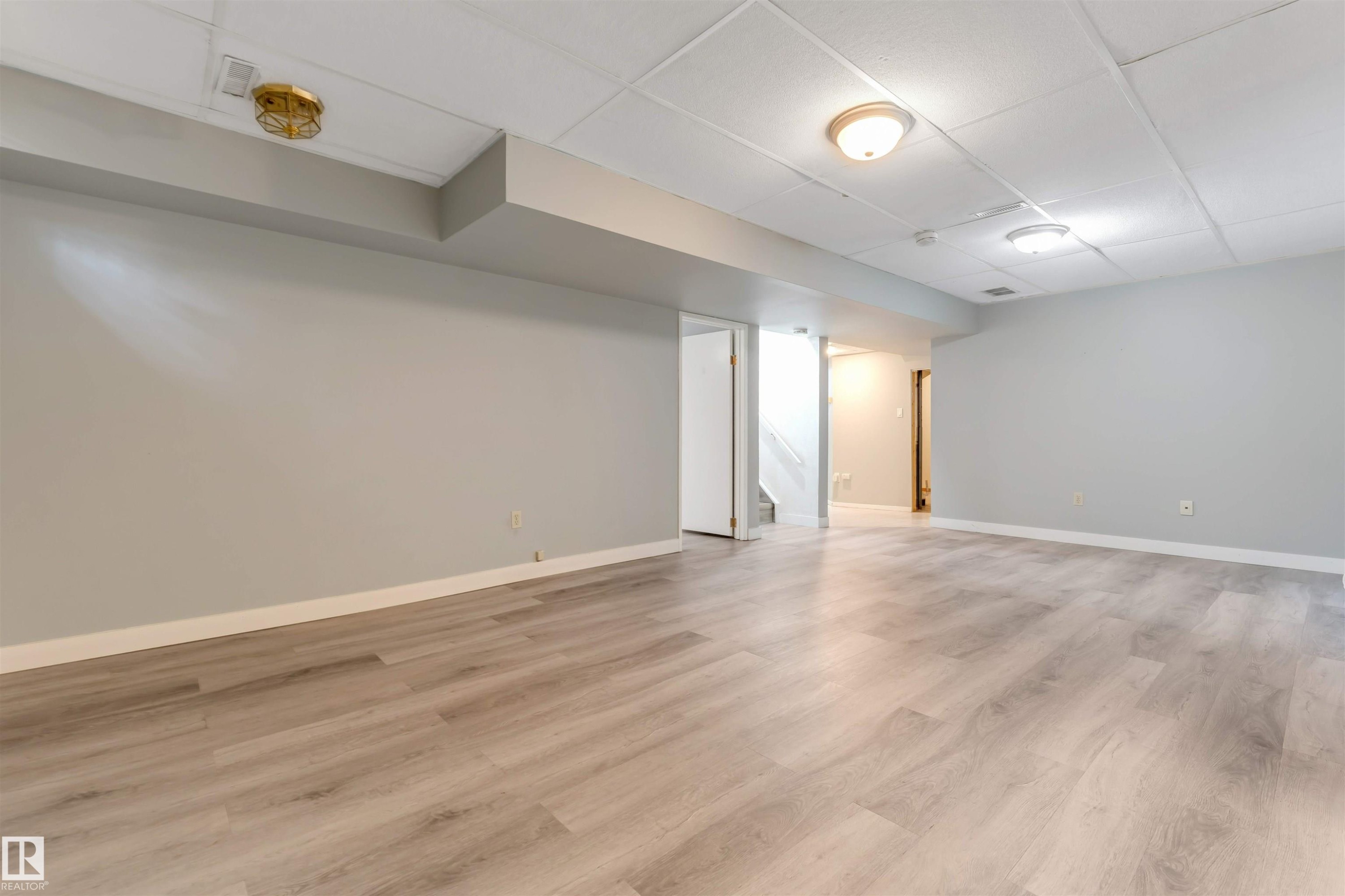 Spacious interior featuring light wood-finish flooring, light gray walls, and white trim - 193 Woodvale Road W, Edmonton, AB