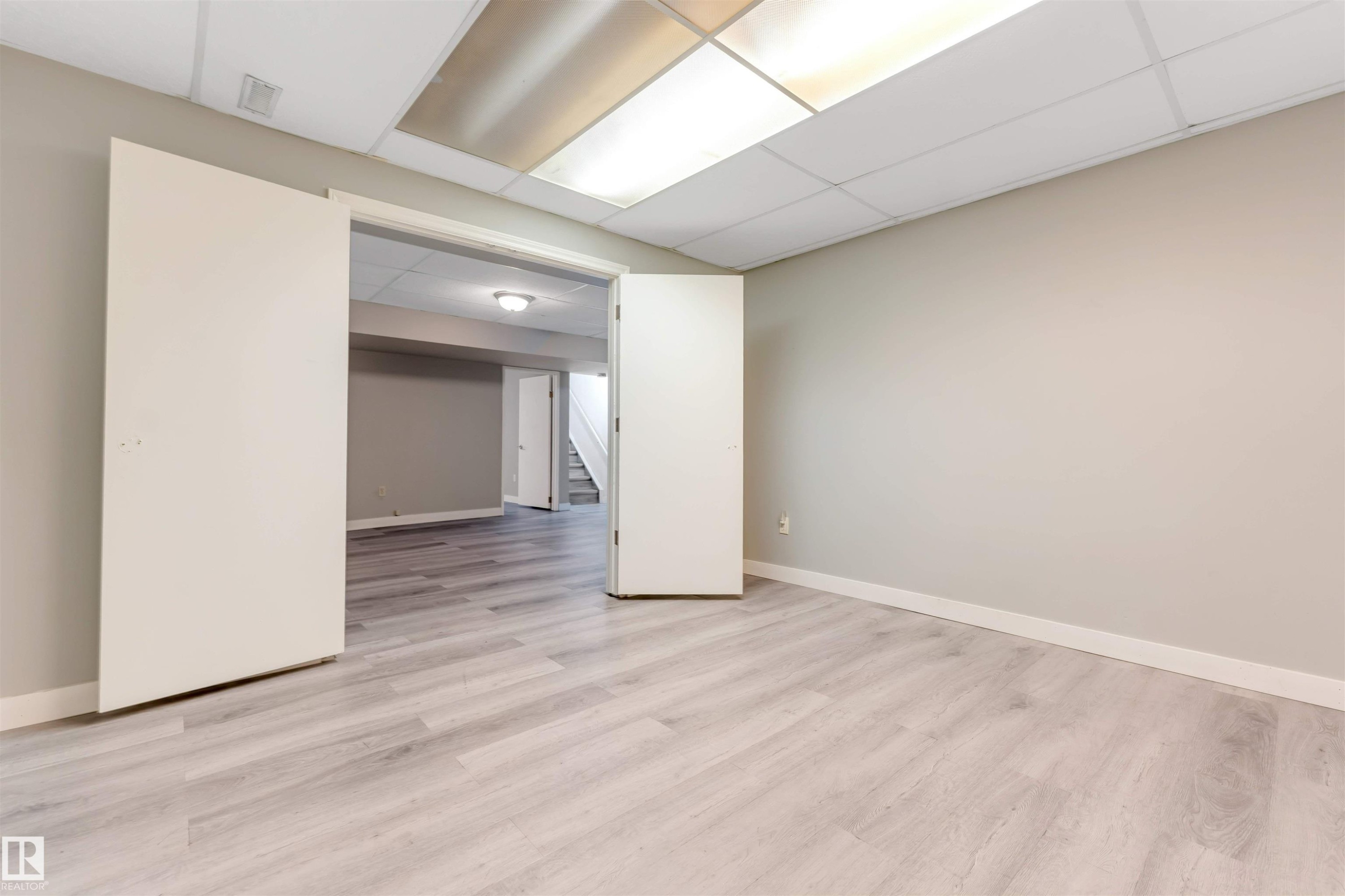 Brightly lit room featuring light wood-finish flooring, neutral wall paint, and white trim - 193 Woodvale Road W, Edmonton, AB