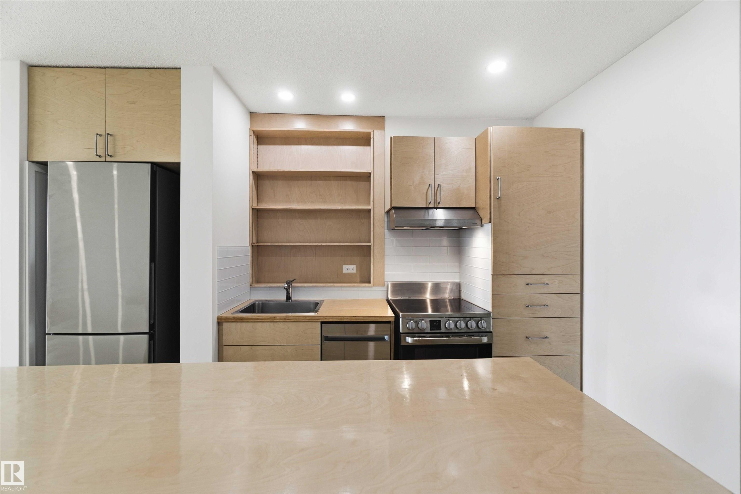 Modern kitchen featuring light wood-finish cabinetry, stainless steel appliances, and recessed lighting - #1008 11307 99 Av Nw, Edmonton, AB