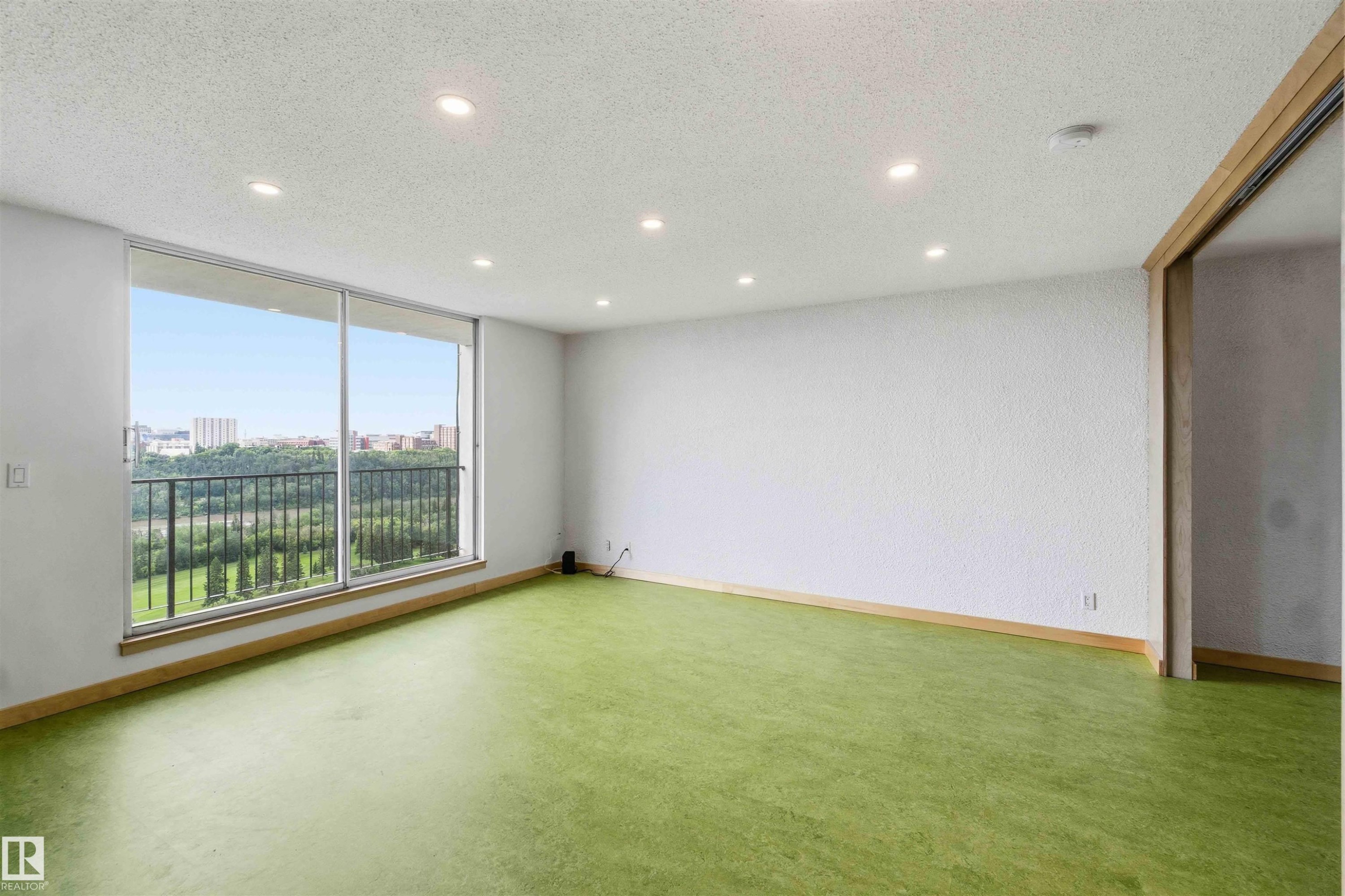 Spacious room featuring floor-to-ceiling windows, recessed lighting, wood-finish trim, and green flooring - #1008 11307 99 Av Nw, Edmonton, AB