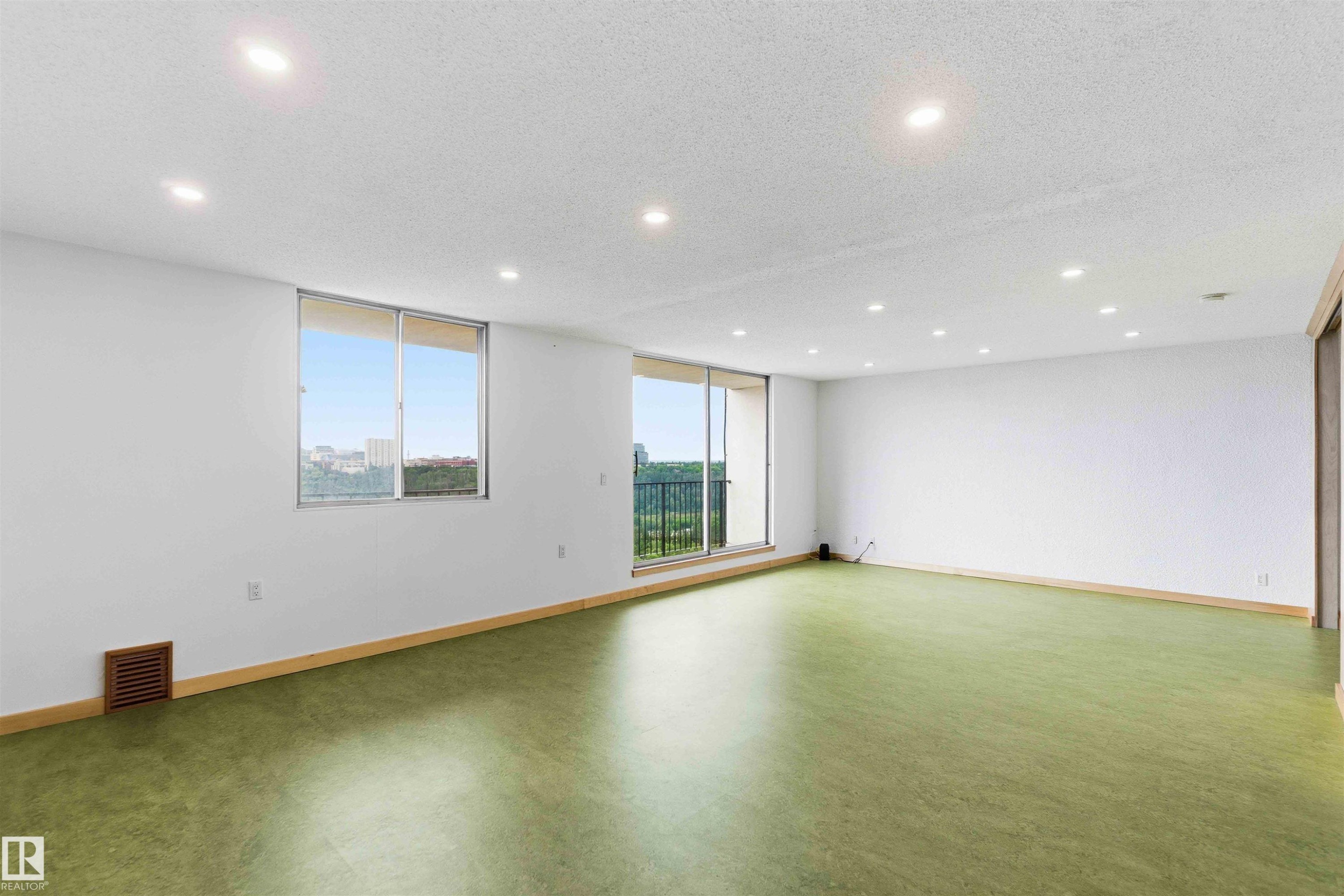 Spacious interior featuring a large window and sliding glass door, both offering high-rise scenery - #1008 11307 99 Av Nw, Edmonton, AB