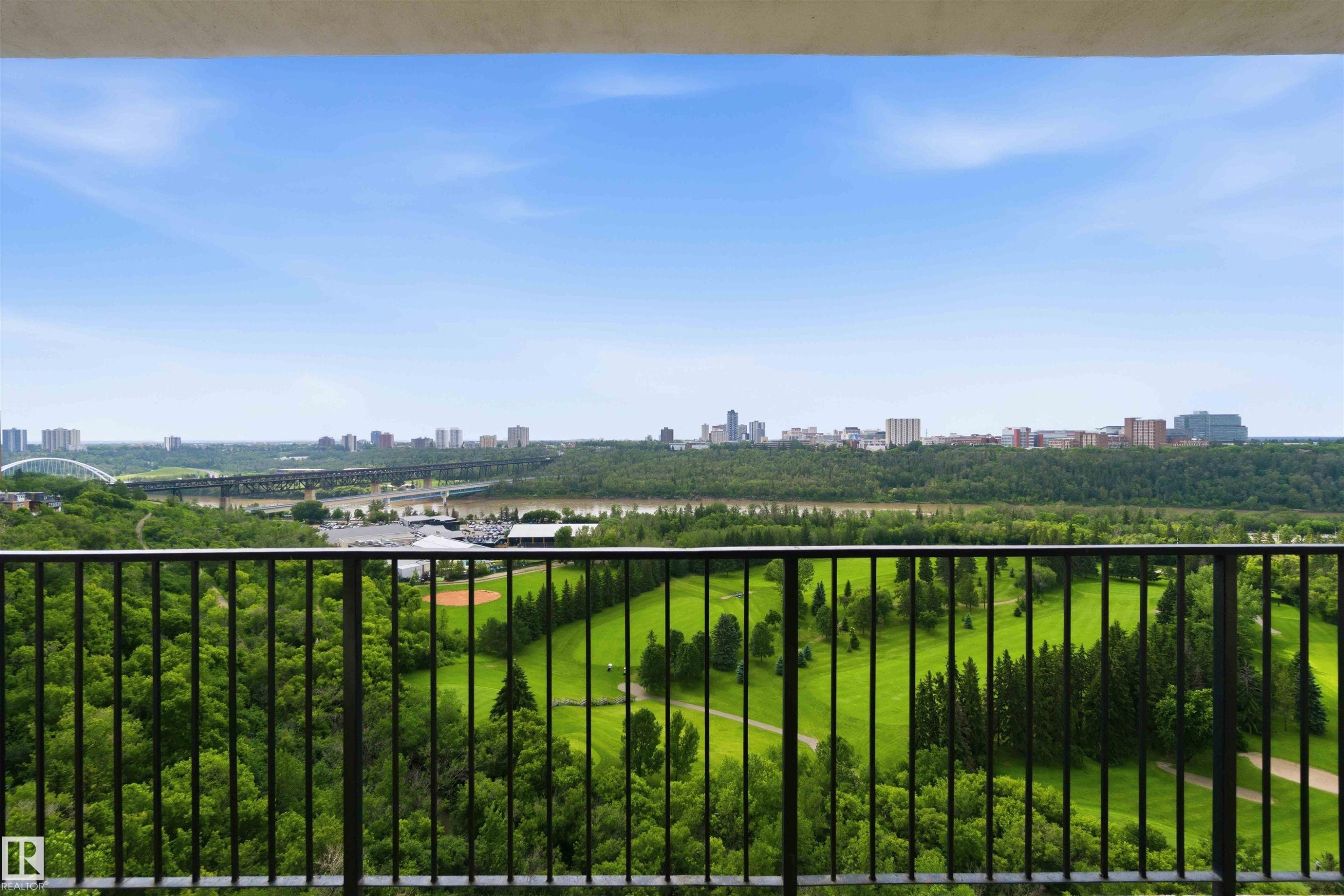 Expansive outdoor space featuring a dark metal railing, offering broad panoramas of a golf course, river, and distant cityscape - #1008 11307 99 Av Nw, Edmonton, AB