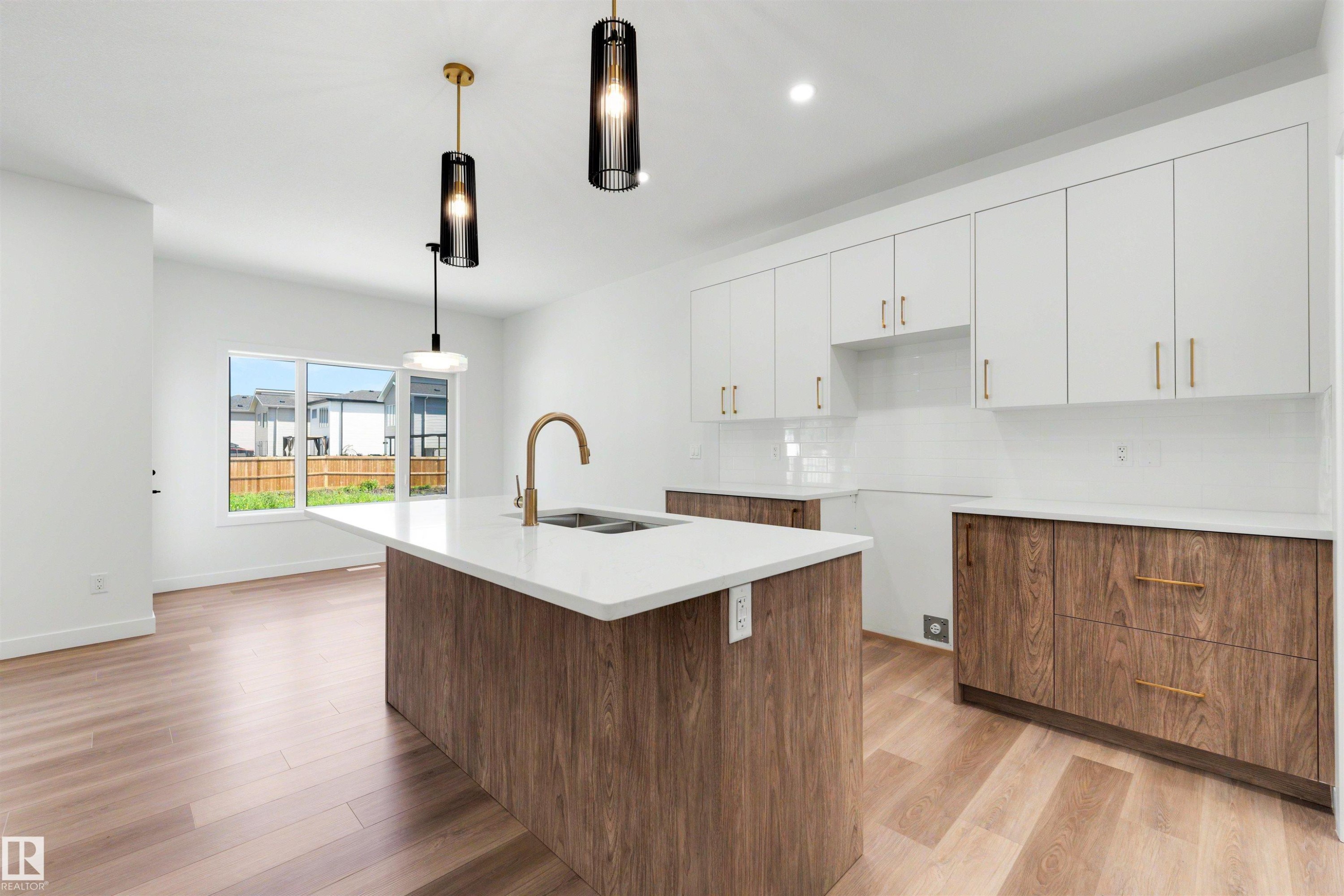 Modern kitchen featuring a central island with an undermount sink, white countertops, and wood-finish cabinetry - 30 Elsinore Place Nw, Edmonton, AB