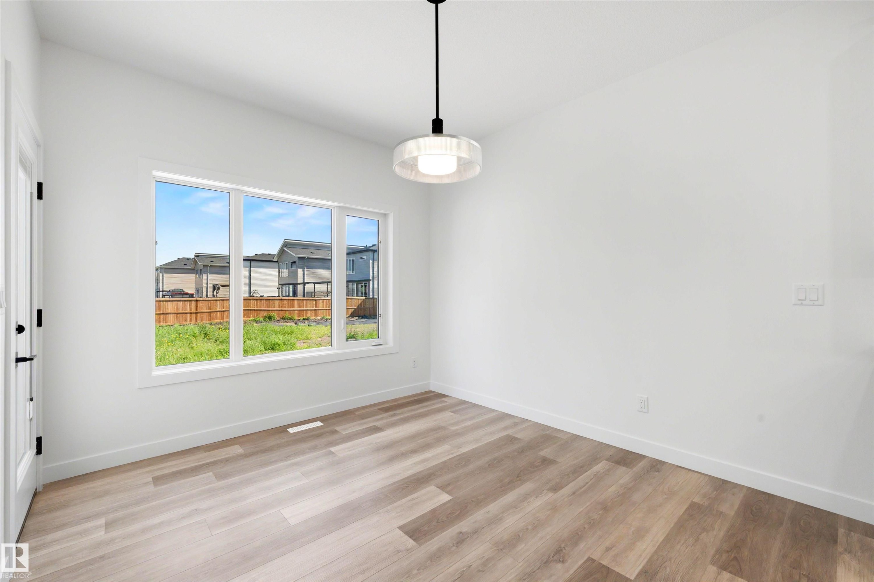 Bright interior space featuring a large three-panel window, wood-finish flooring, and crisp white walls - 30 Elsinore Place Nw, Edmonton, AB