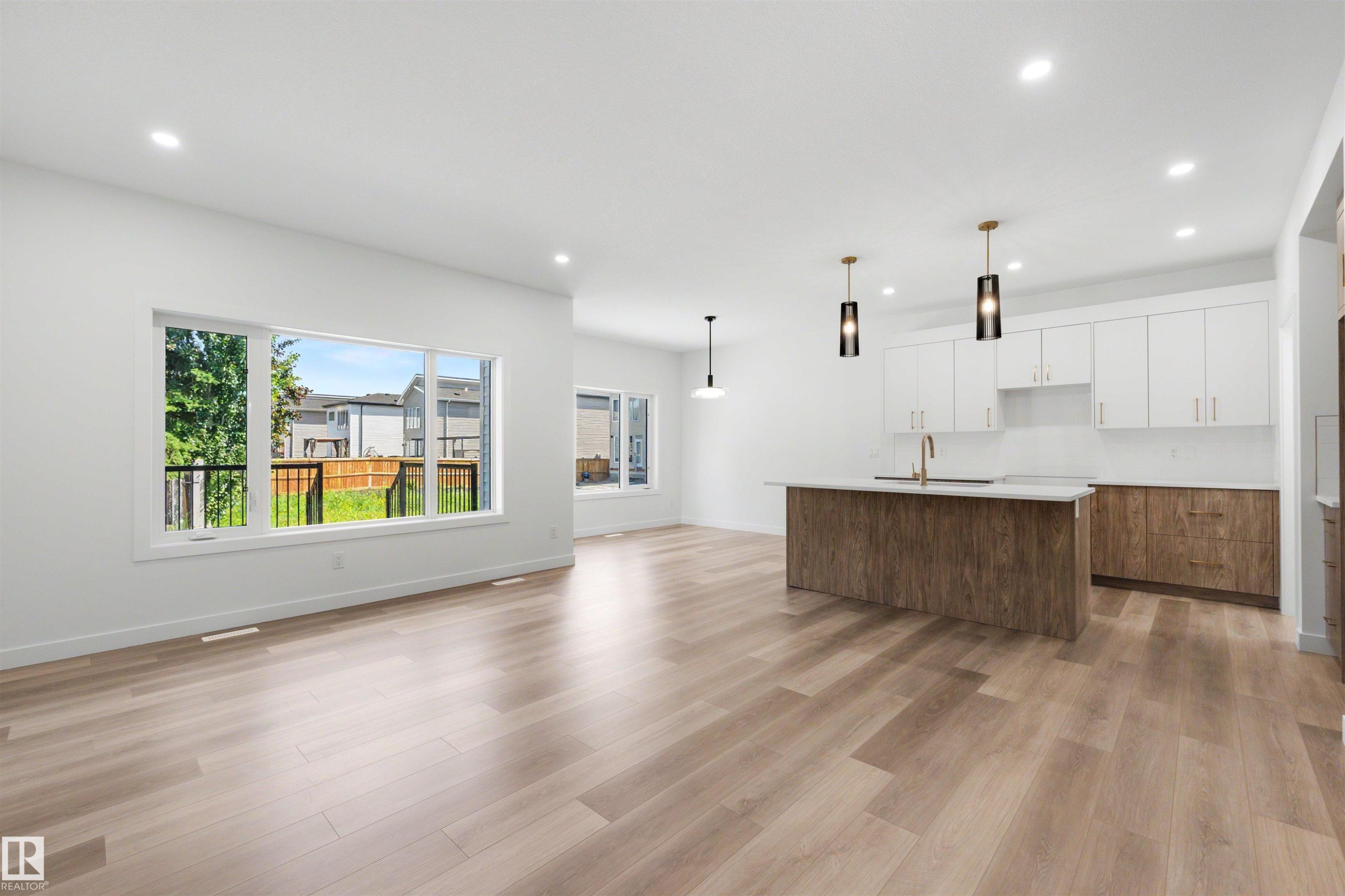 Open-concept living space featuring wood-finish flooring, recessed lighting, and large windows - 30 Elsinore Place Nw, Edmonton, AB