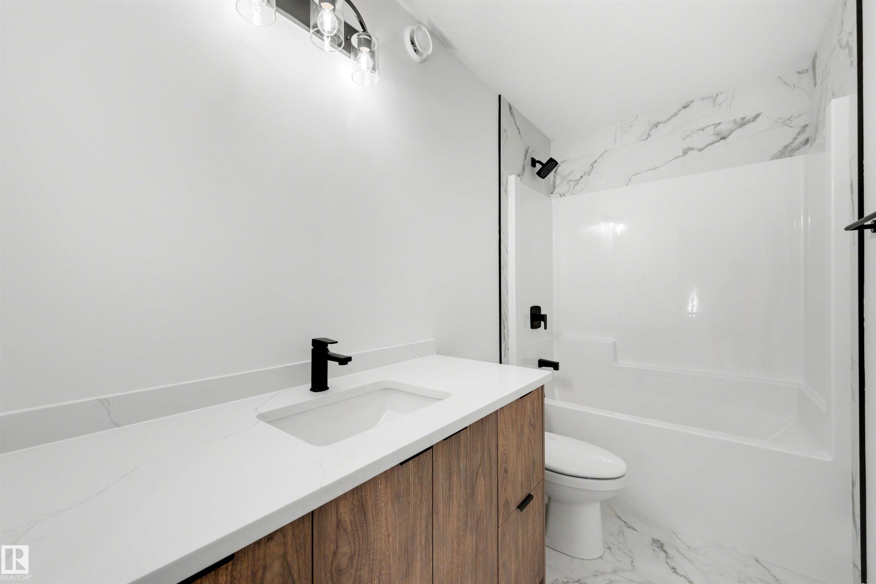 Contemporary bathroom featuring a wood-finish vanity with a white countertop and integrated sink, matte black faucet, and a wall-mounted light fixture - 30 Elsinore Place Nw, Edmonton, AB