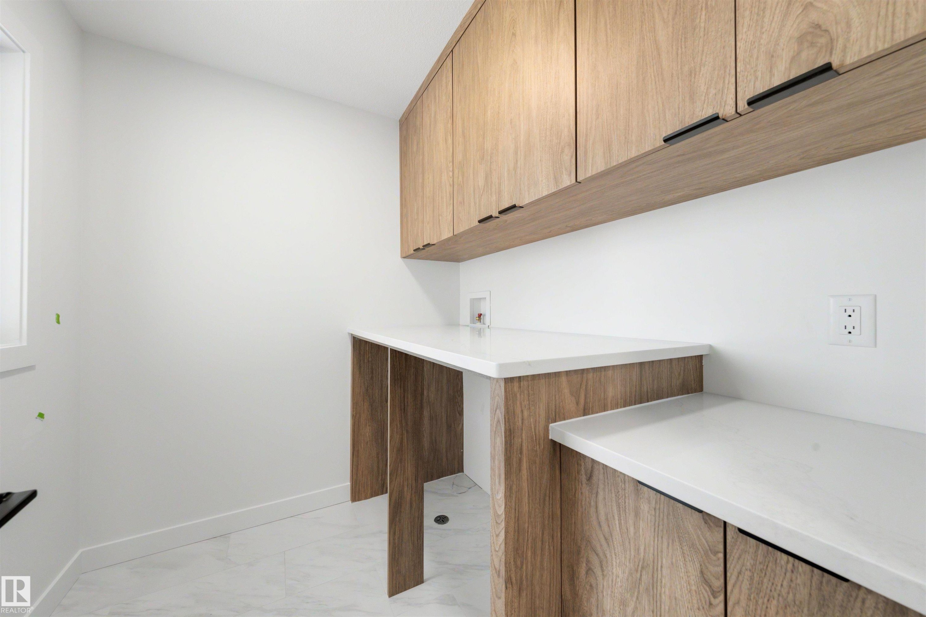 Laundry area featuring light wood-finish cabinetry, white countertops, and light tile flooring - 30 Elsinore Place Nw, Edmonton, AB