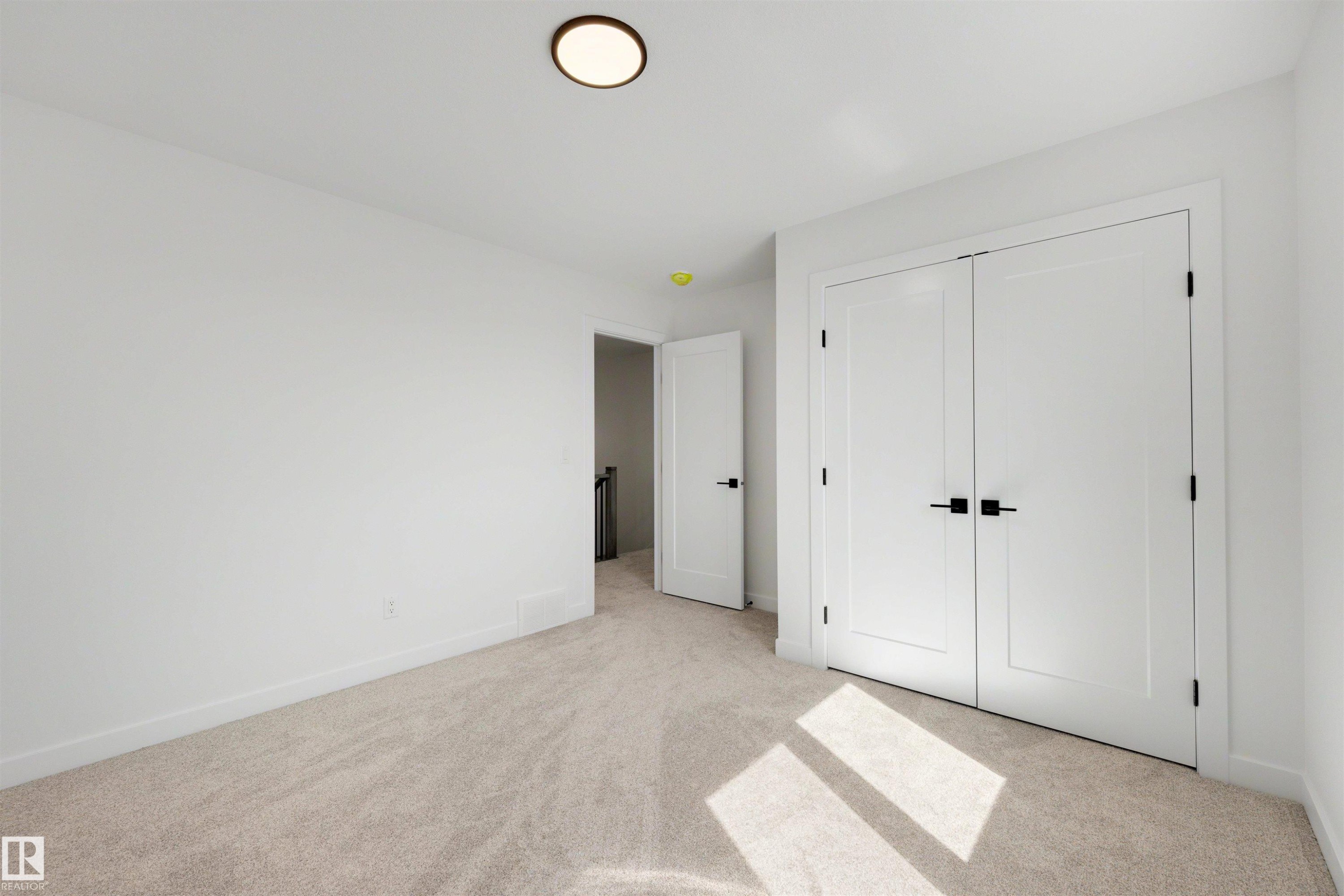 Neutral-toned carpet flooring complements the white walls and trim - 30 Elsinore Place Nw, Edmonton, AB