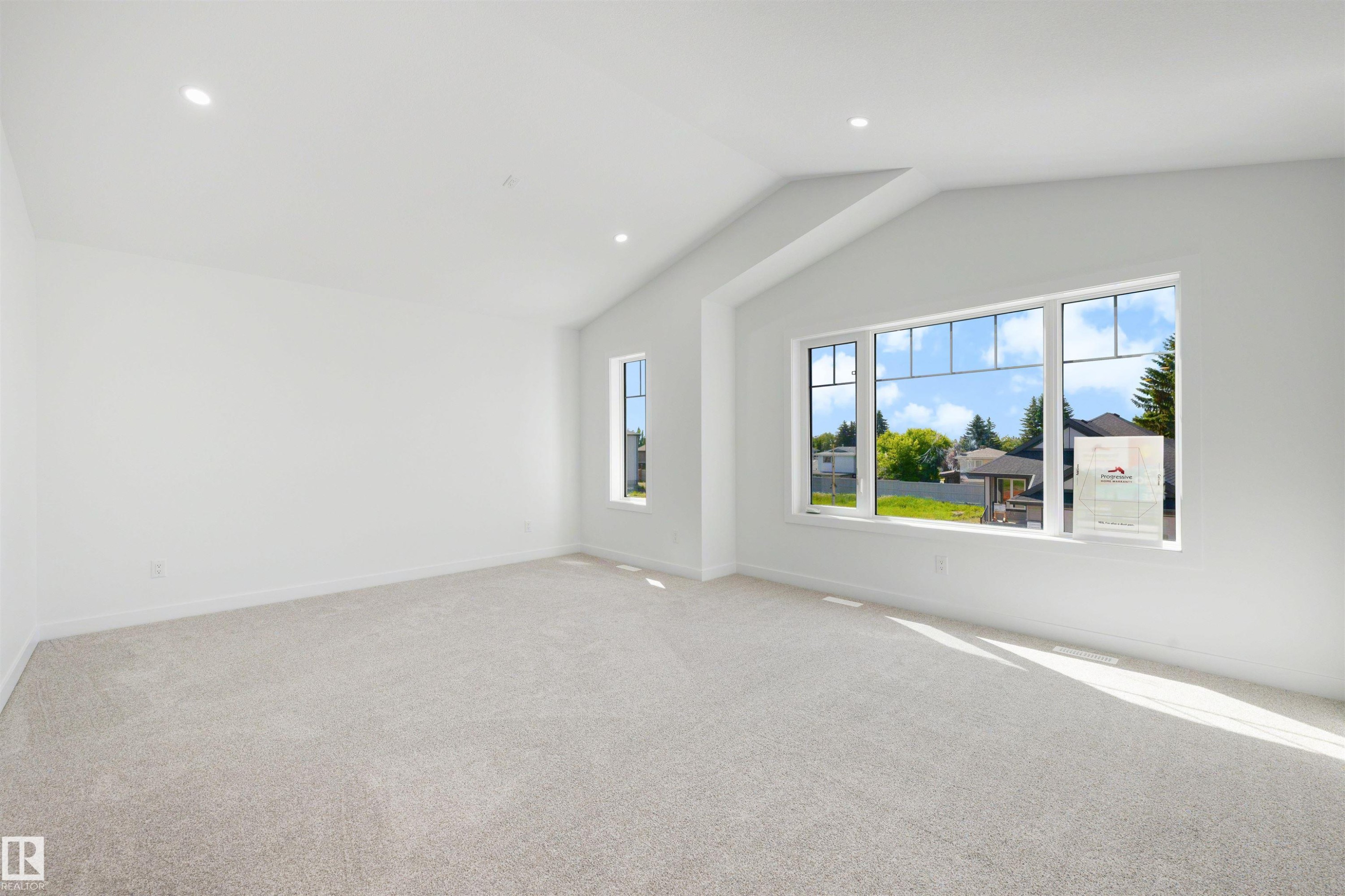 Spacious room featuring vaulted ceilings, recessed lighting, neutral carpeting, and a large window with multiple panes - 30 Elsinore Place Nw, Edmonton, AB