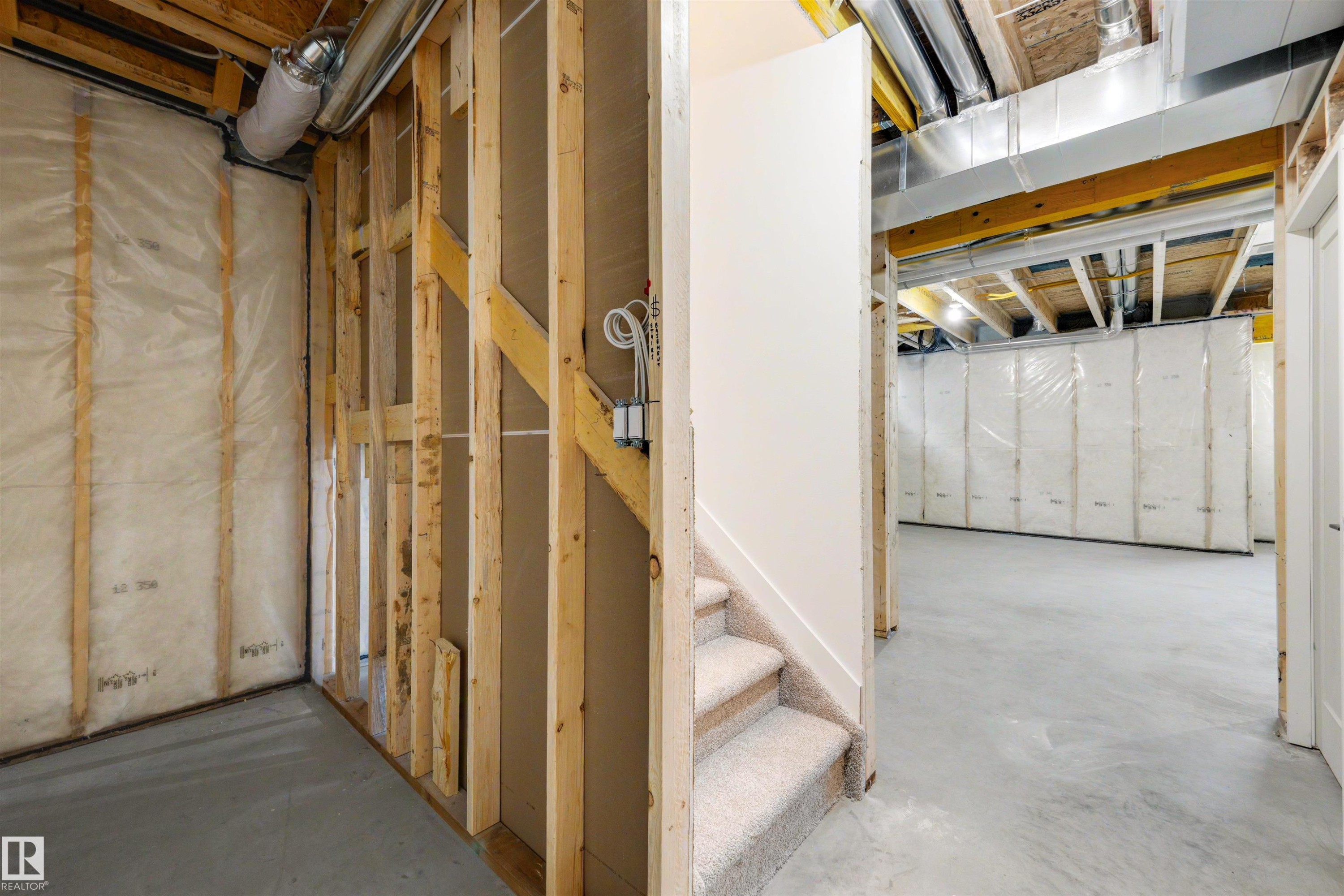Unfinished basement featuring concrete flooring, exposed wood framing, insulated walls, visible ductwork, and a carpeted staircase - 30 Elsinore Place Nw, Edmonton, AB