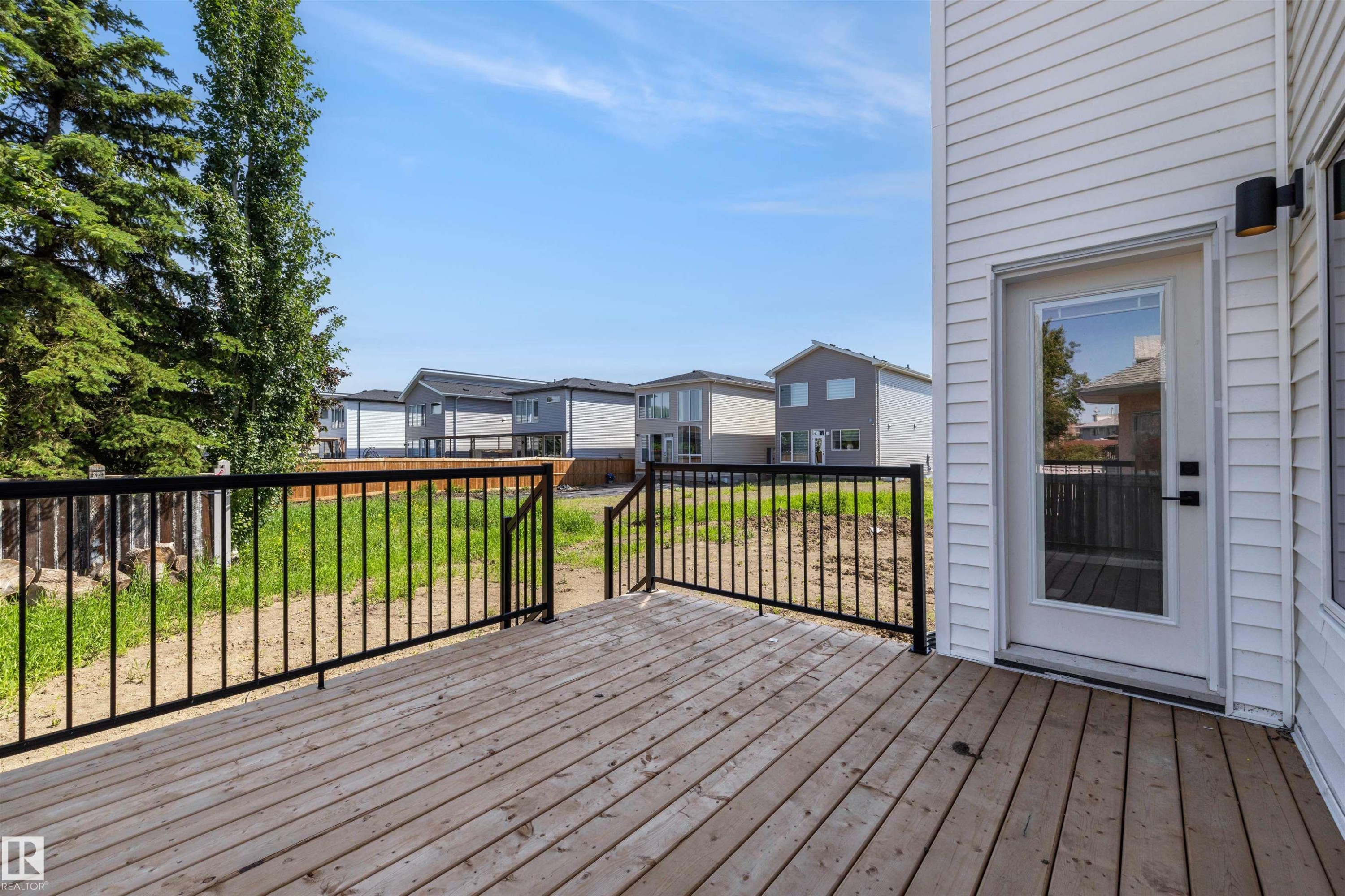 Expansive wooden deck featuring black metal railings and direct access to the interior via a glass-paneled door - 30 Elsinore Place Nw, Edmonton, AB