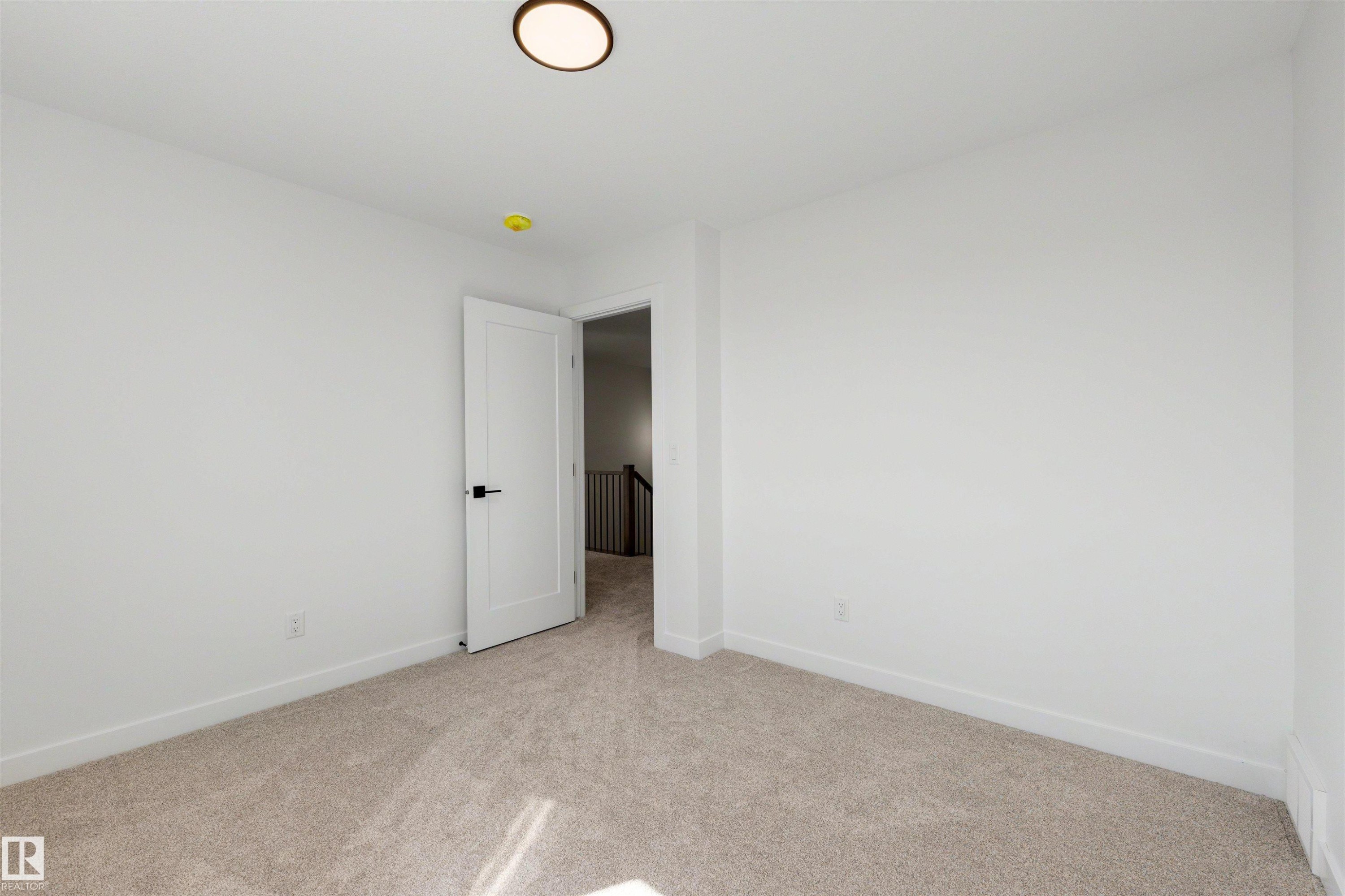 Neutral wall finishes with a modern door featuring matte black hardware, recessed lighting, and soft carpet flooring - 30 Elsinore Place Nw, Edmonton, AB