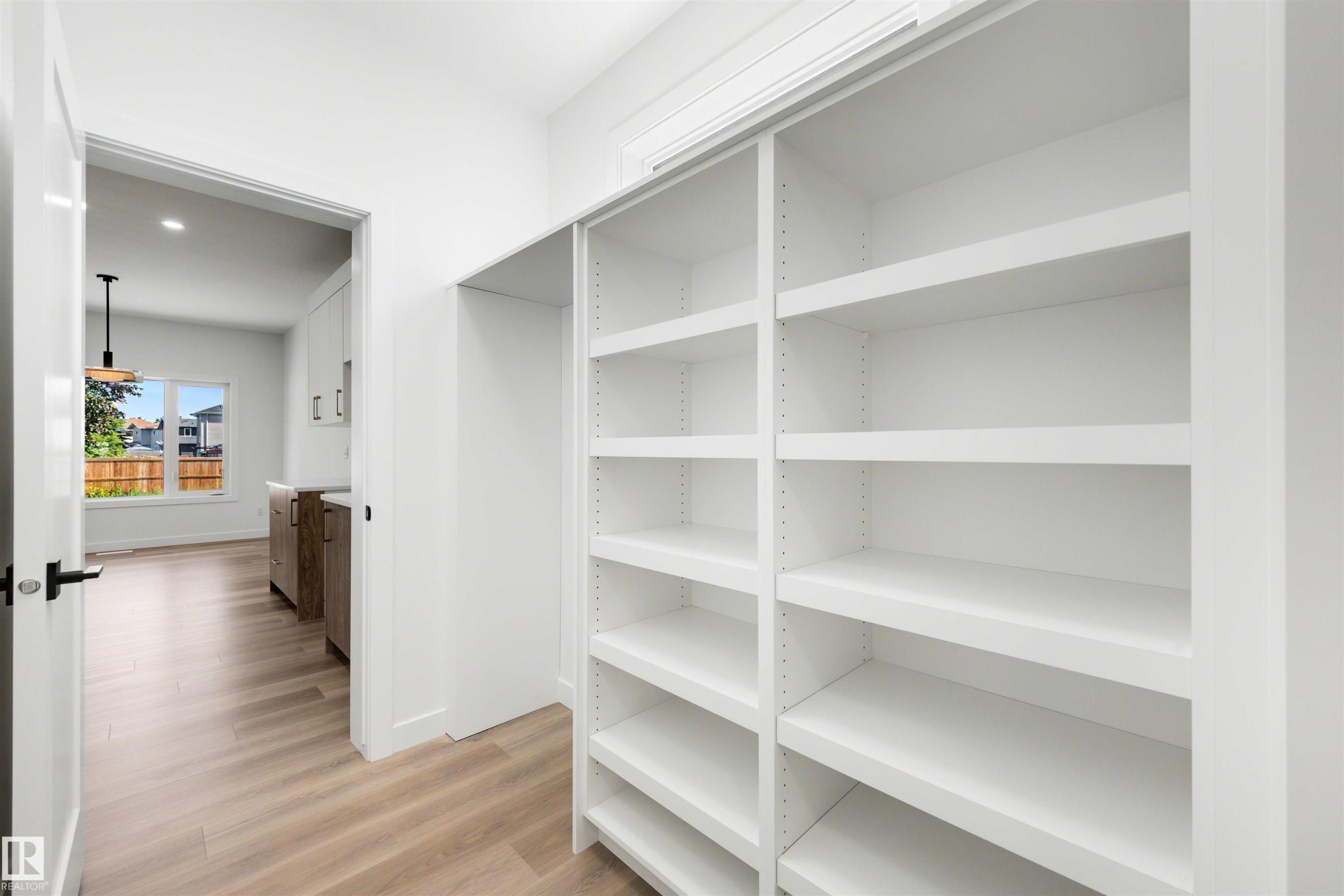 White built-in shelving offering extensive storage, complemented by light wood-finish flooring - 30 Elsinore Place Nw, Edmonton, AB