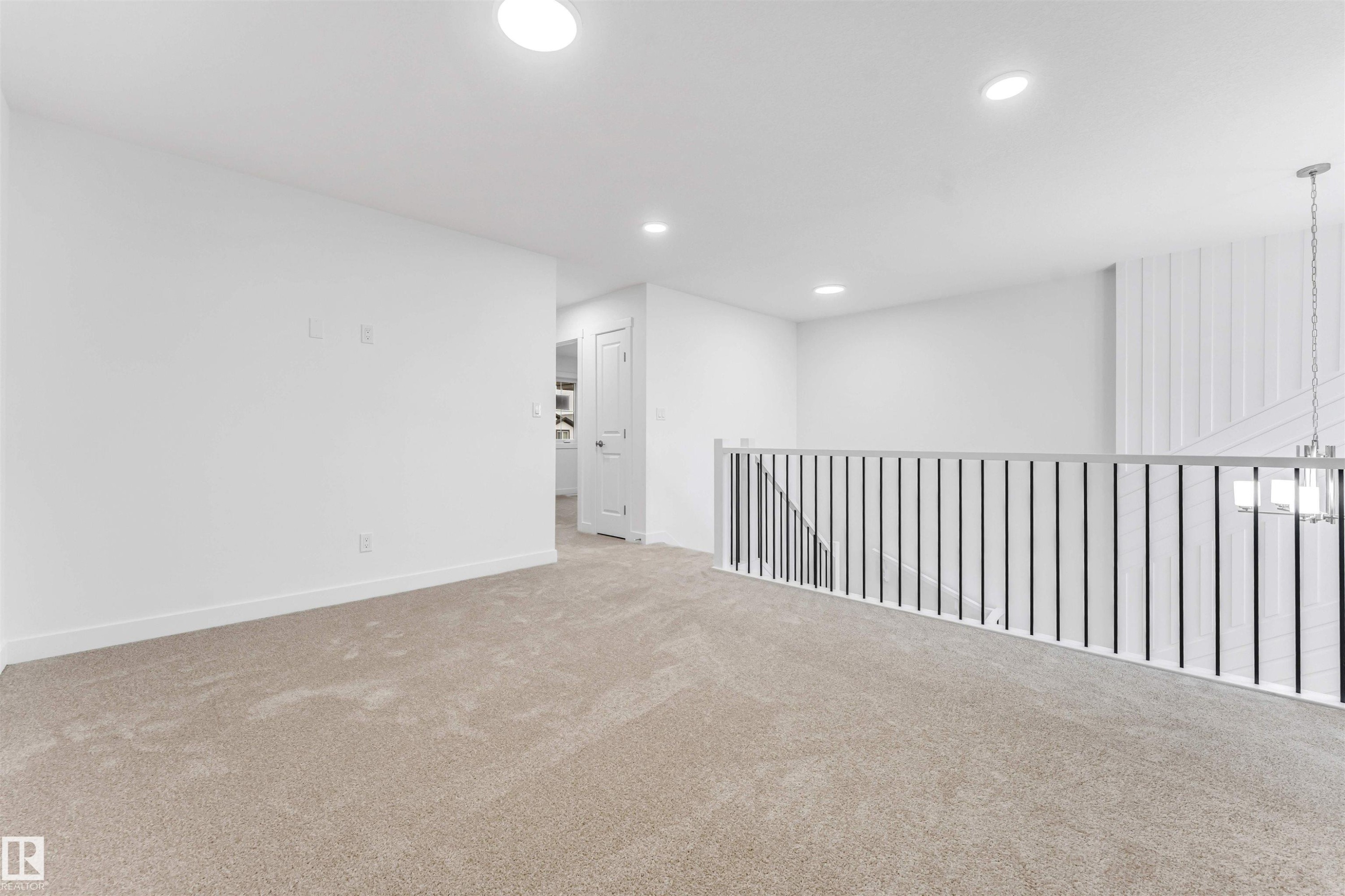 Spacious carpeted landing featuring recessed lighting, a contemporary stair railing with black balusters, and a shiplap accent wall - 1972 210 Street, Edmonton, AB