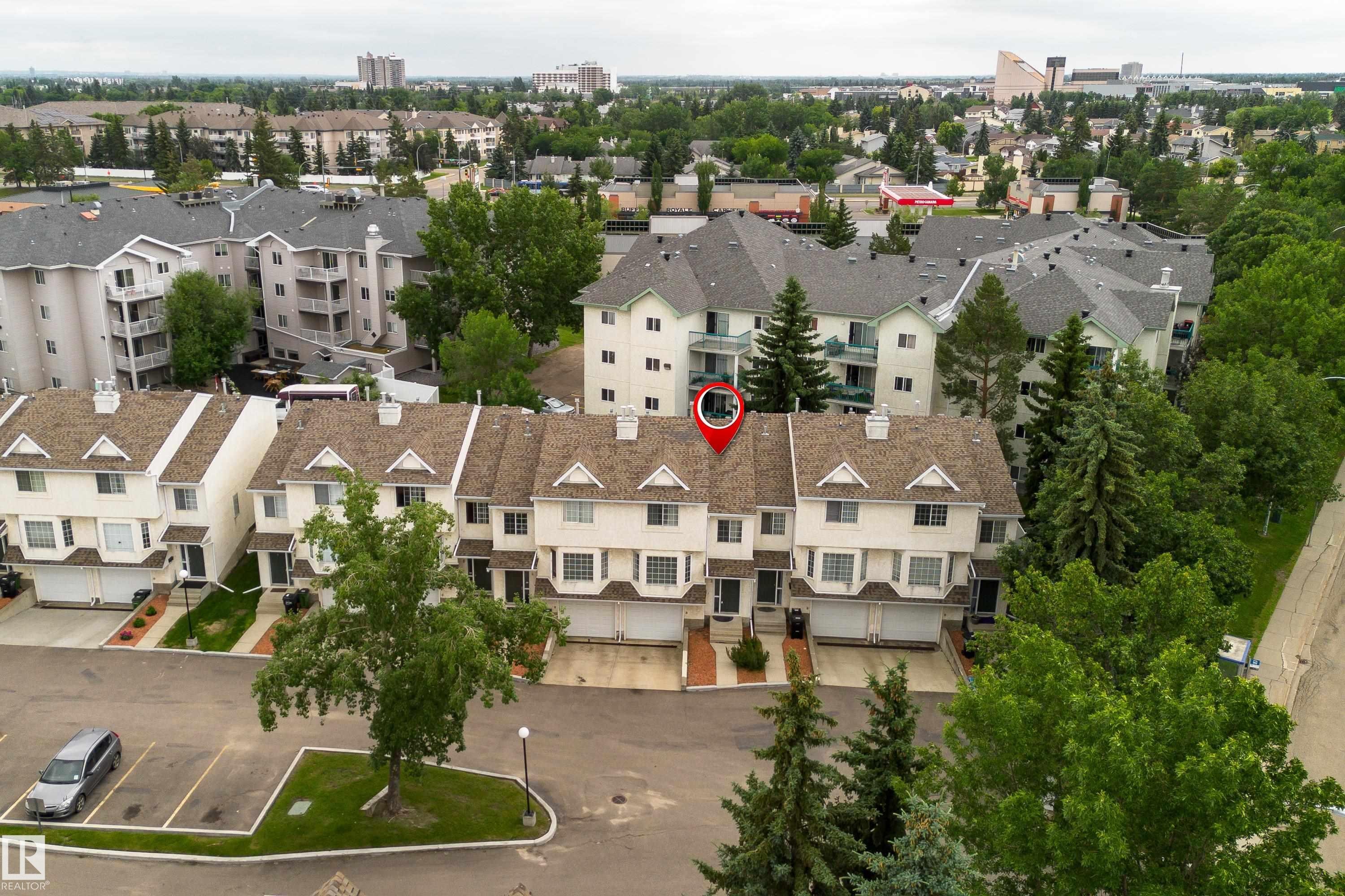 Townhome featuring a gabled roof, light-colored siding, attached garage, and individual front entrances - 3 9703 174 Street, Edmonton, AB