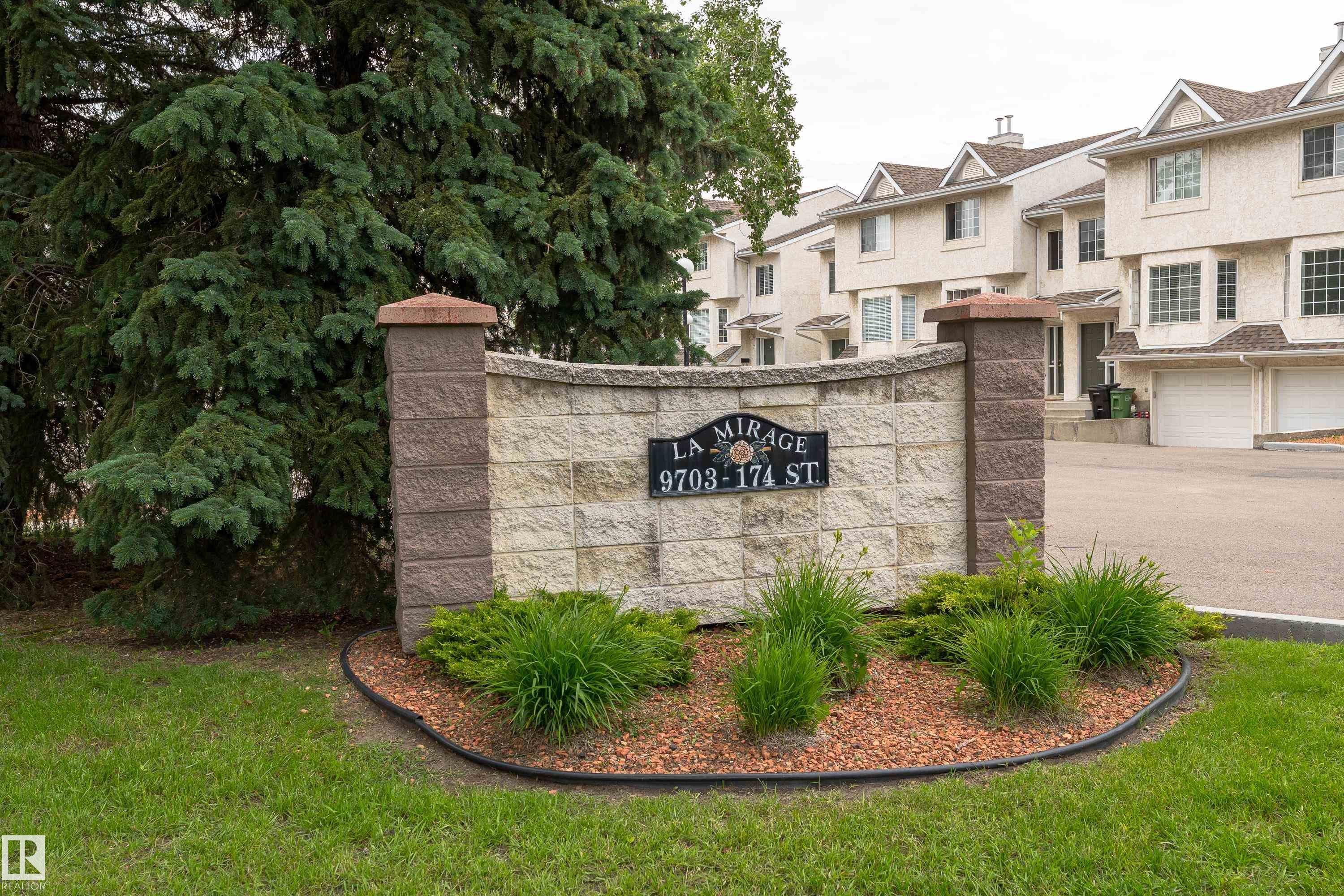 Stone and block monument sign with raised lettering, featuring a landscaped base with ground cover and mulch - 3 9703 174 Street, Edmonton, AB