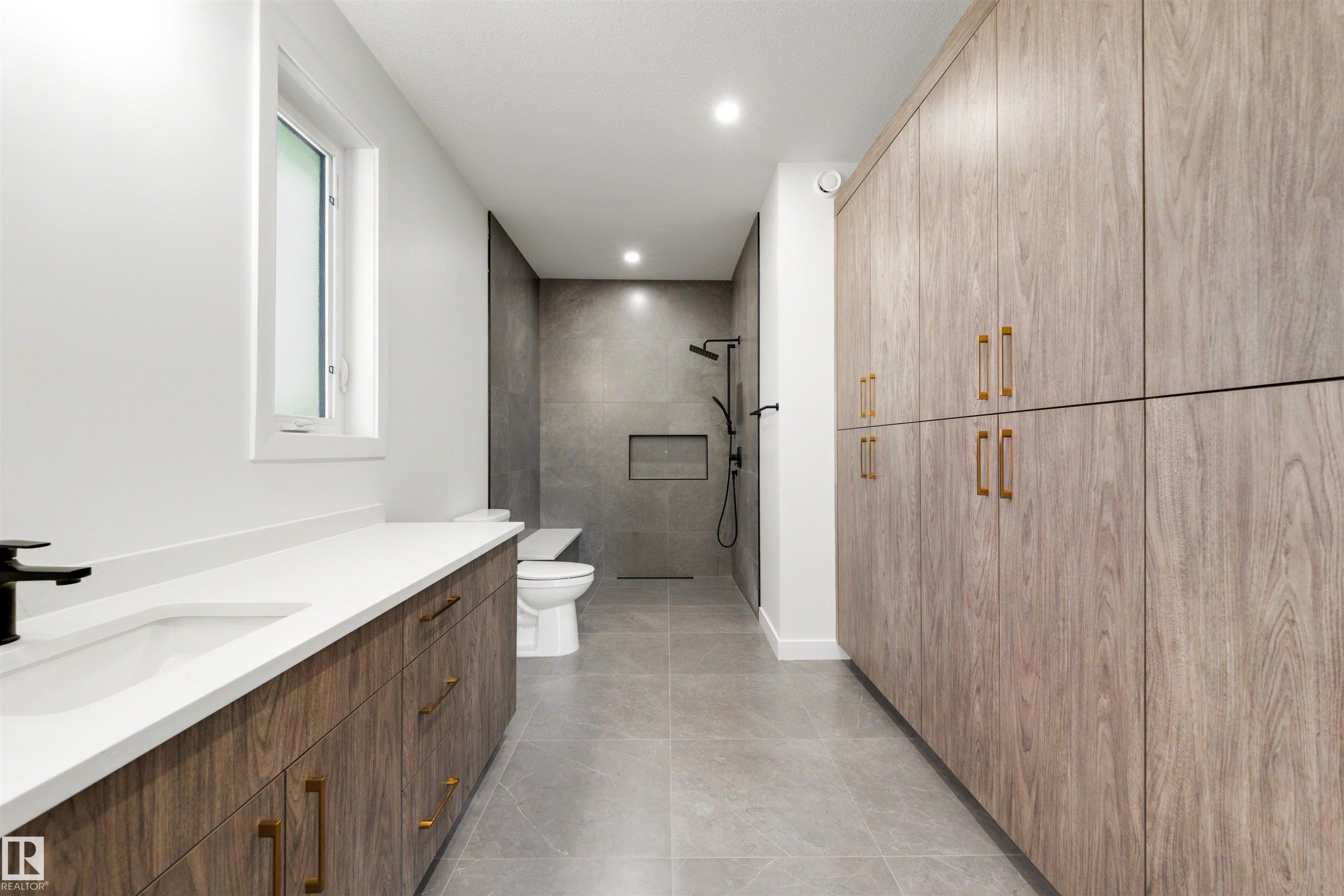 Spacious bathroom featuring a double vanity with wood-finish cabinetry, white countertop, and a built-in sink - 39 Elsinore Place, Edmonton, AB