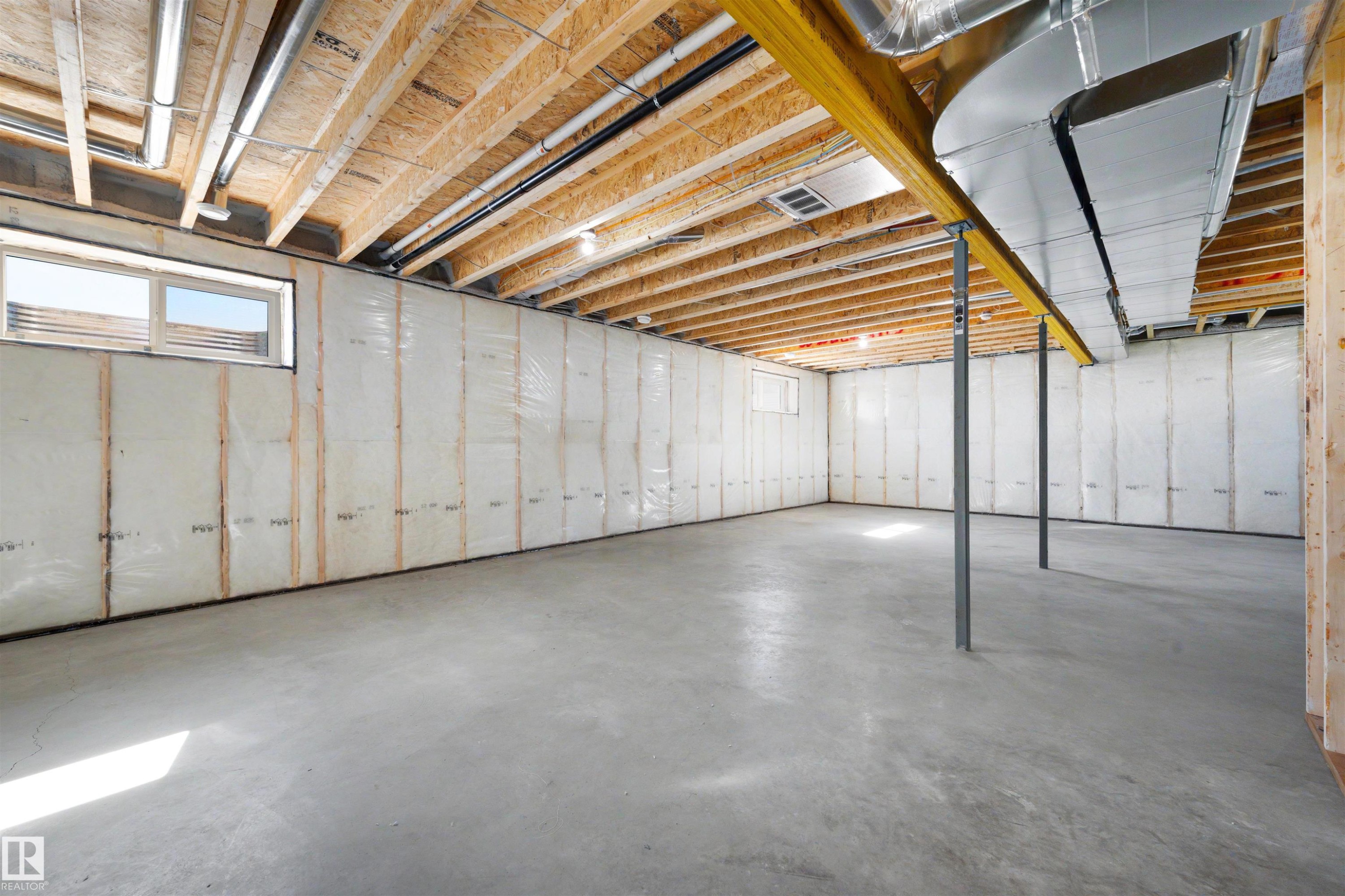 Unfinished lower level featuring concrete flooring, exposed wood joists, a steel support beam, two windows, and insulated walls - 39 Elsinore Place, Edmonton, AB
