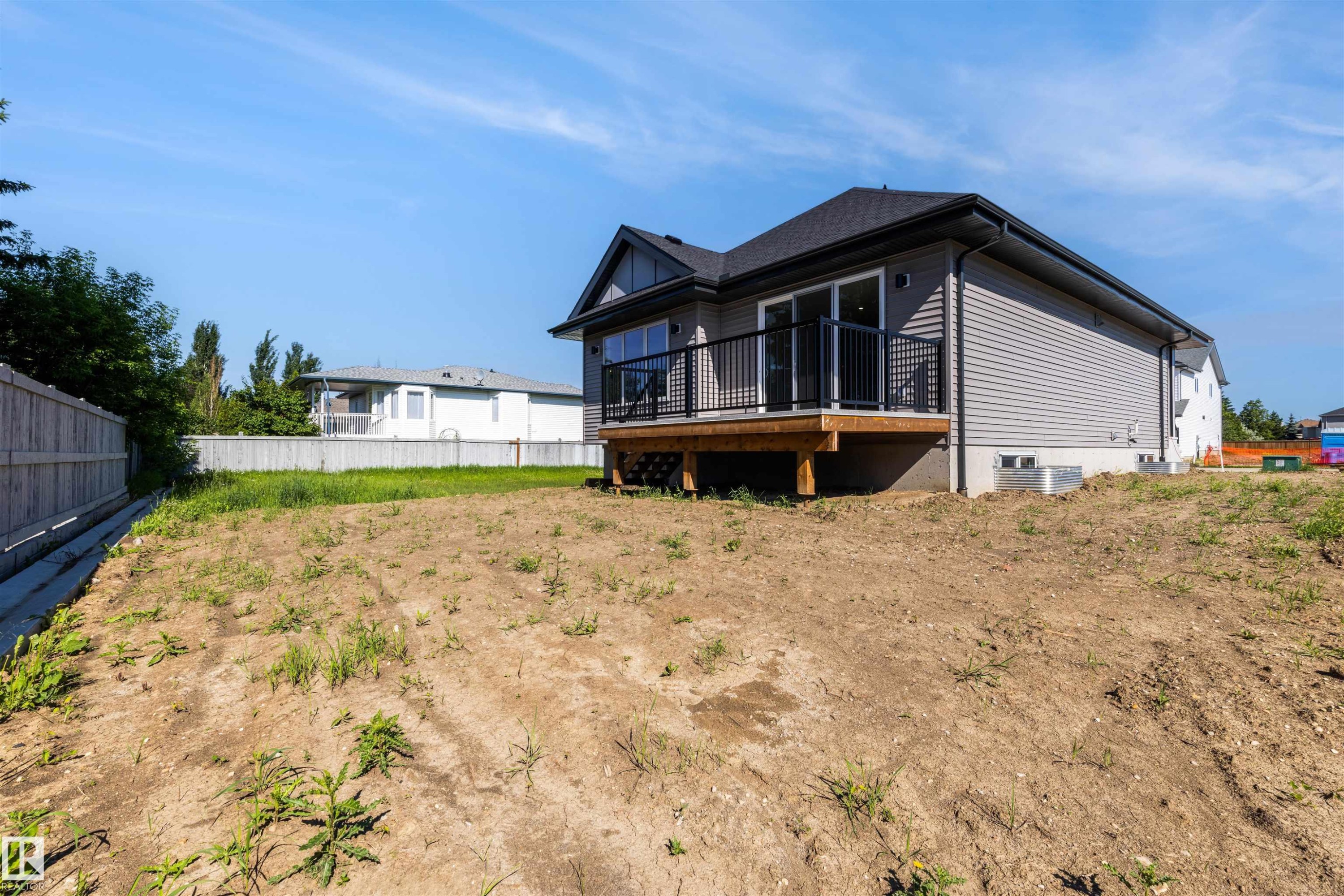 Newly constructed home featuring grey siding, a dark shingle roof, and a rear deck with black railings - 39 Elsinore Place, Edmonton, AB