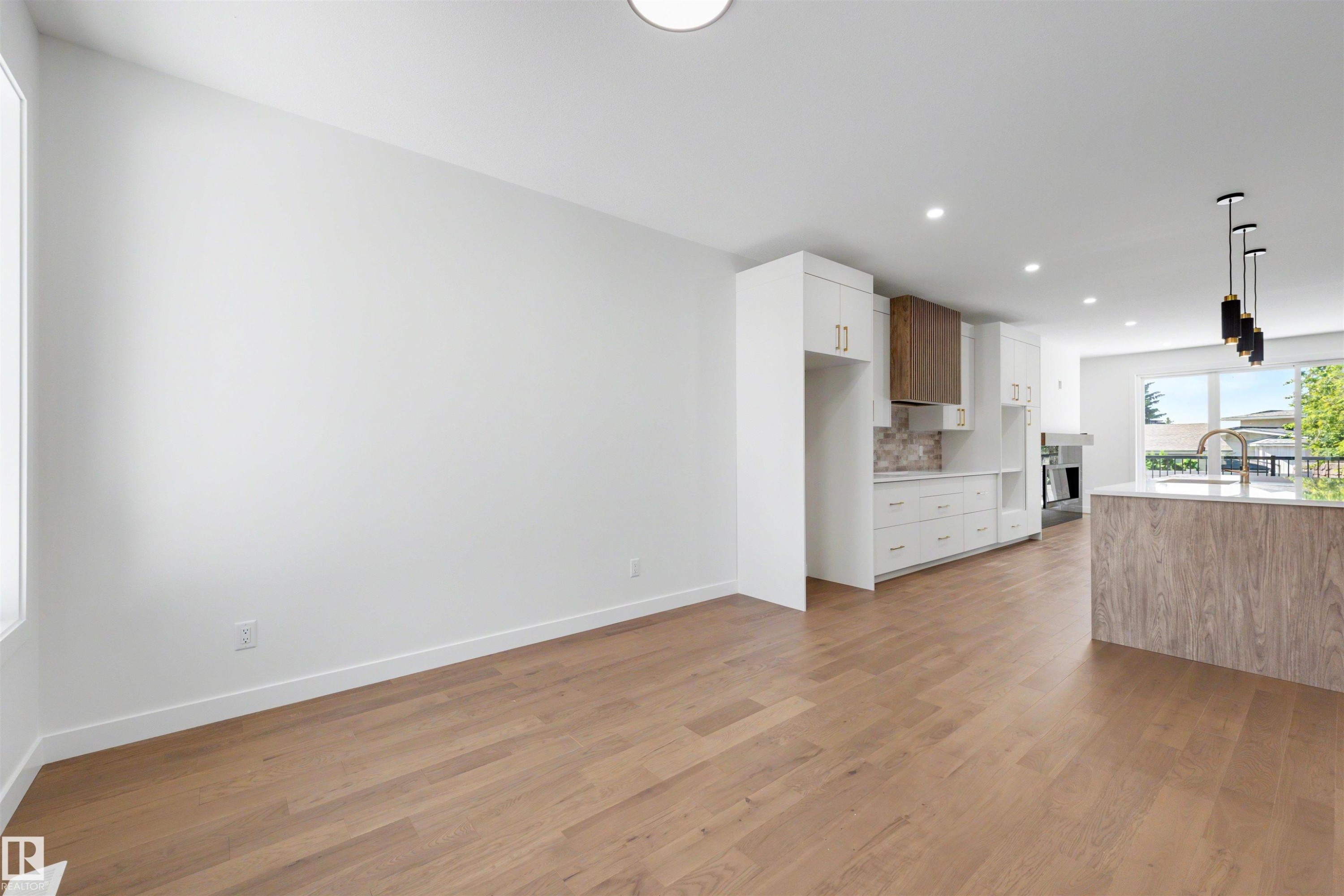 Open-concept living area featuring light wood-finish flooring, white walls, recessed lighting, and a modern kitchen - 39 Elsinore Place, Edmonton, AB