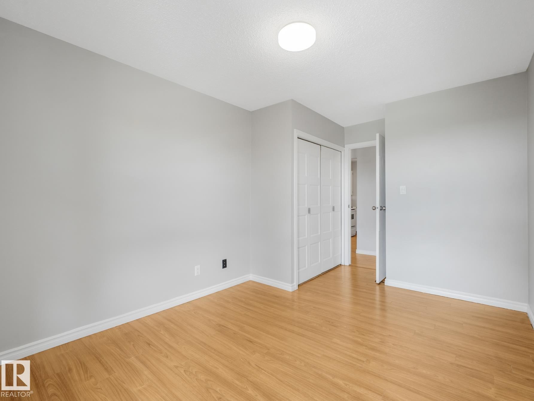 Interior room featuring wood-finish flooring, light gray walls, and white baseboards - #301 10528 29 Av Nw, Edmonton, AB