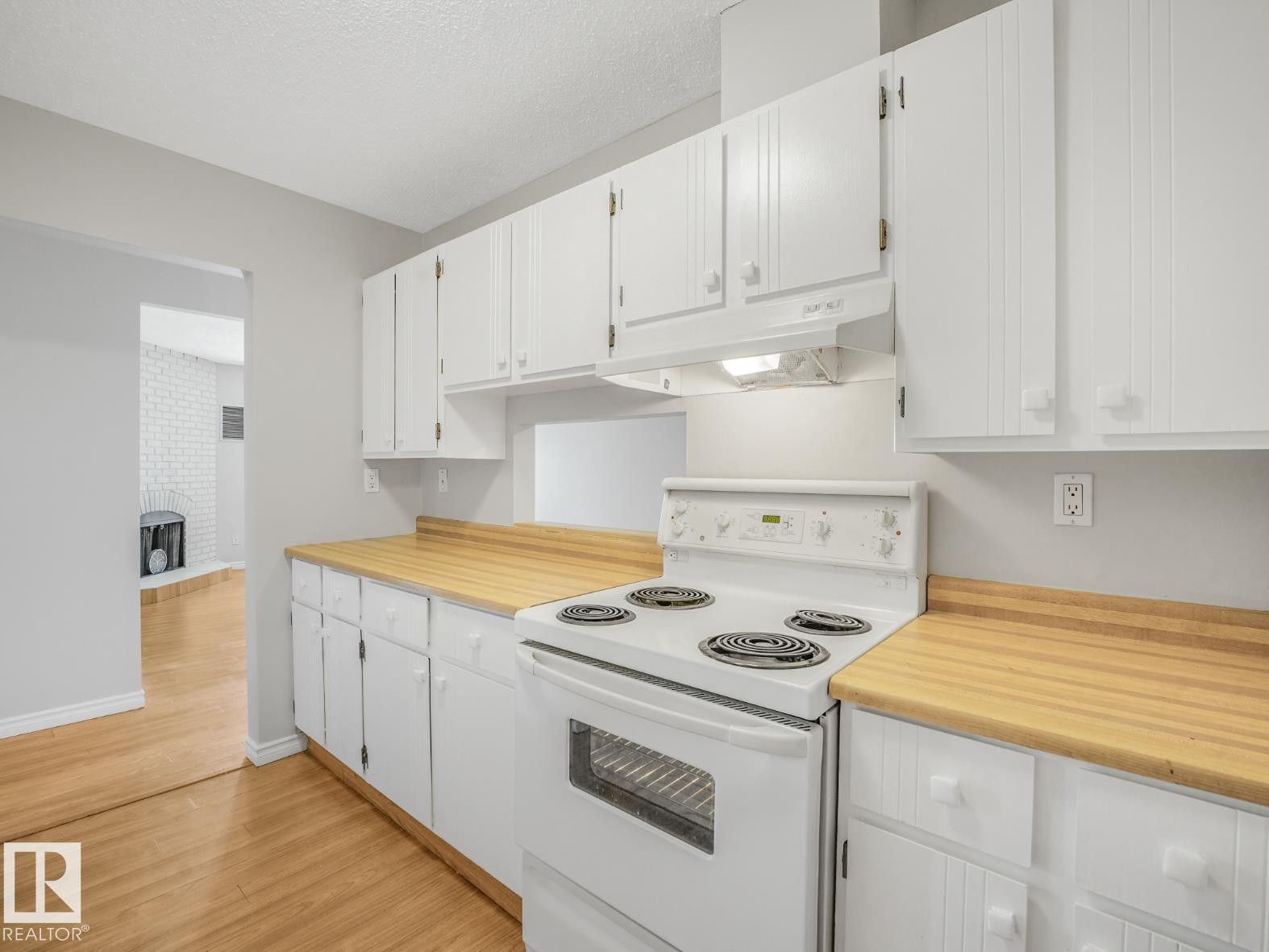 Kitchen featuring white cabinetry, wood-finish countertops, and an electric range with an overhead exhaust fan - #301 10528 29 Av Nw, Edmonton, AB