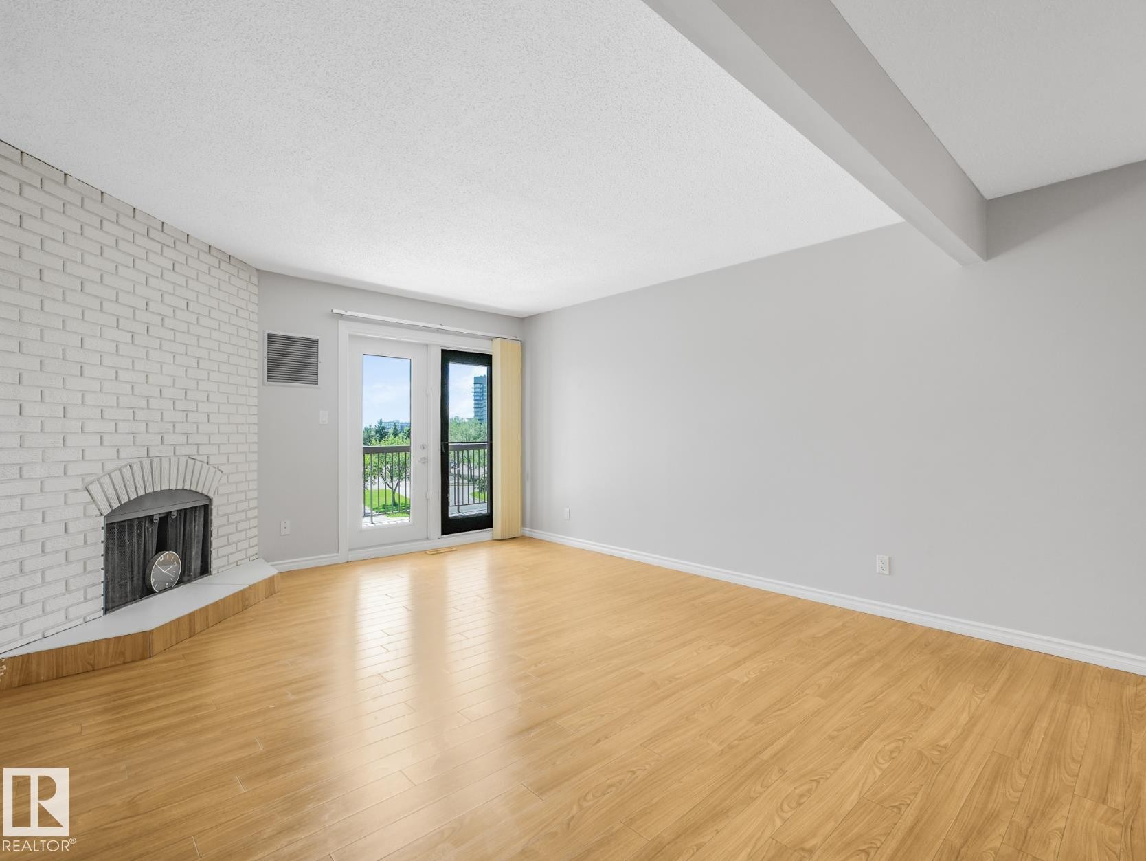 Living space featuring light wood-finish flooring and a painted brick fireplace - #301 10528 29 Av Nw, Edmonton, AB