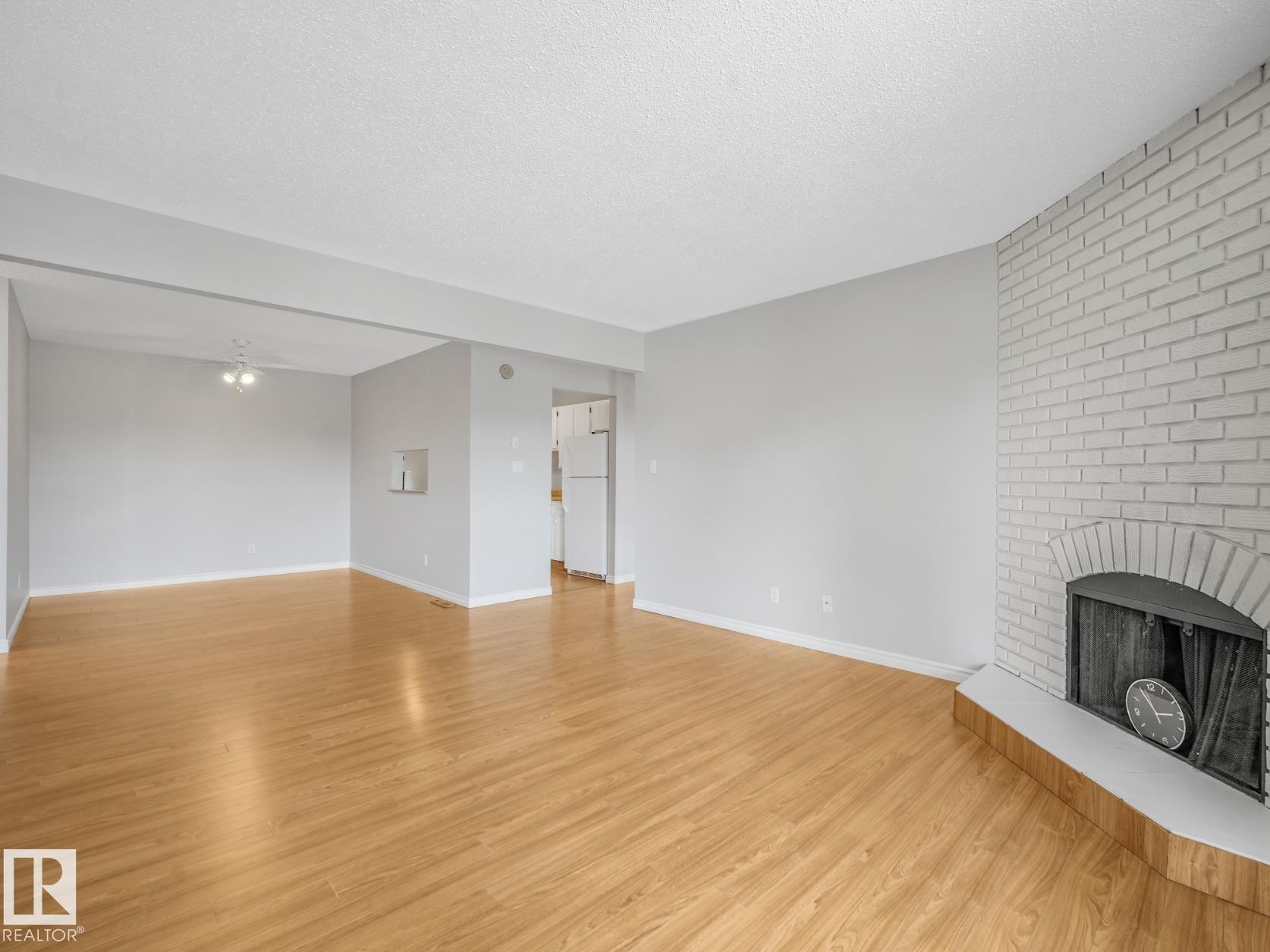Light wood-finish flooring complements the neutral wall color in this open living space - #301 10528 29 Av Nw, Edmonton, AB